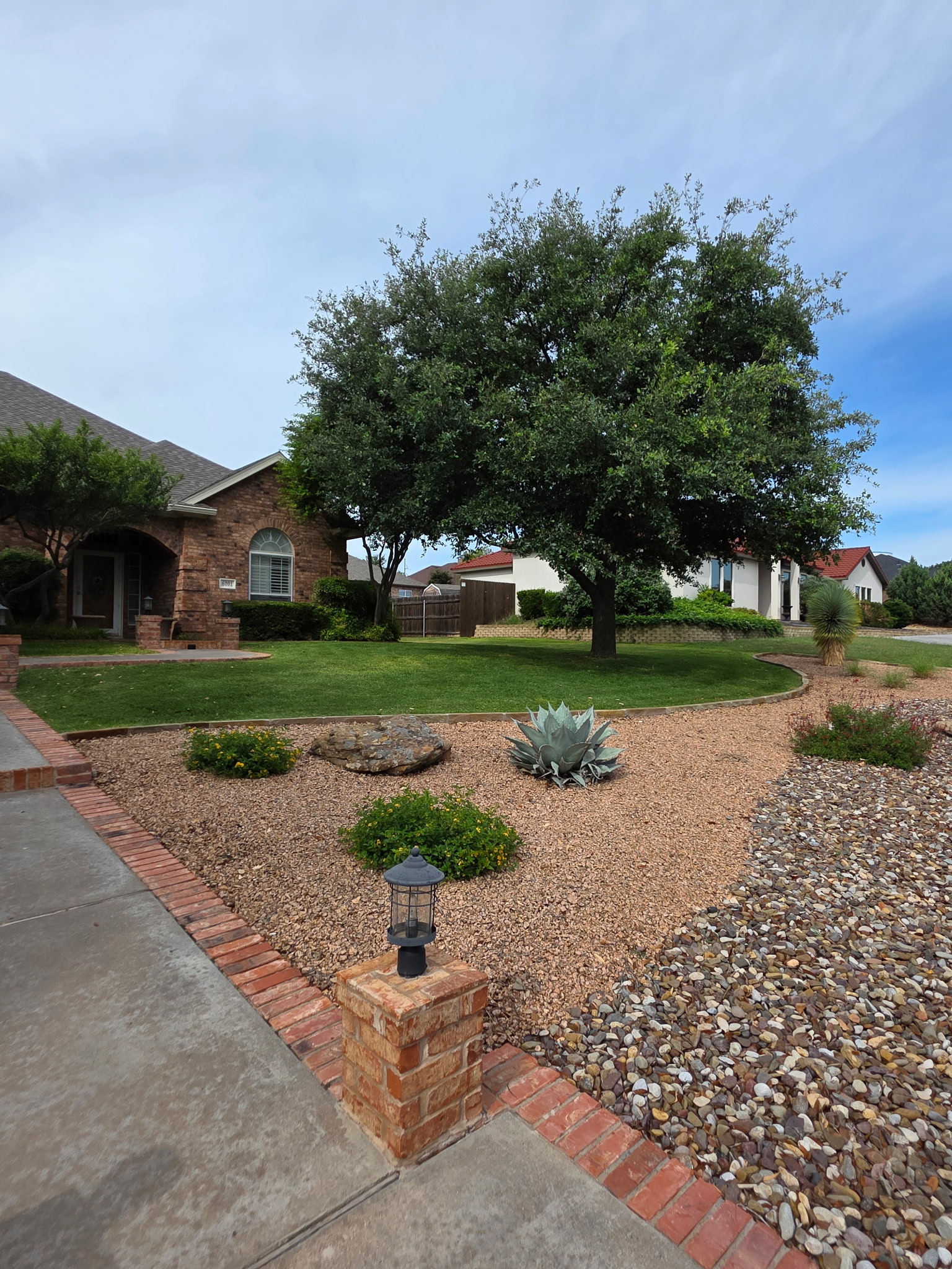 xeriscaped residential landscape with gravel bed, agave, river rock, and lawn