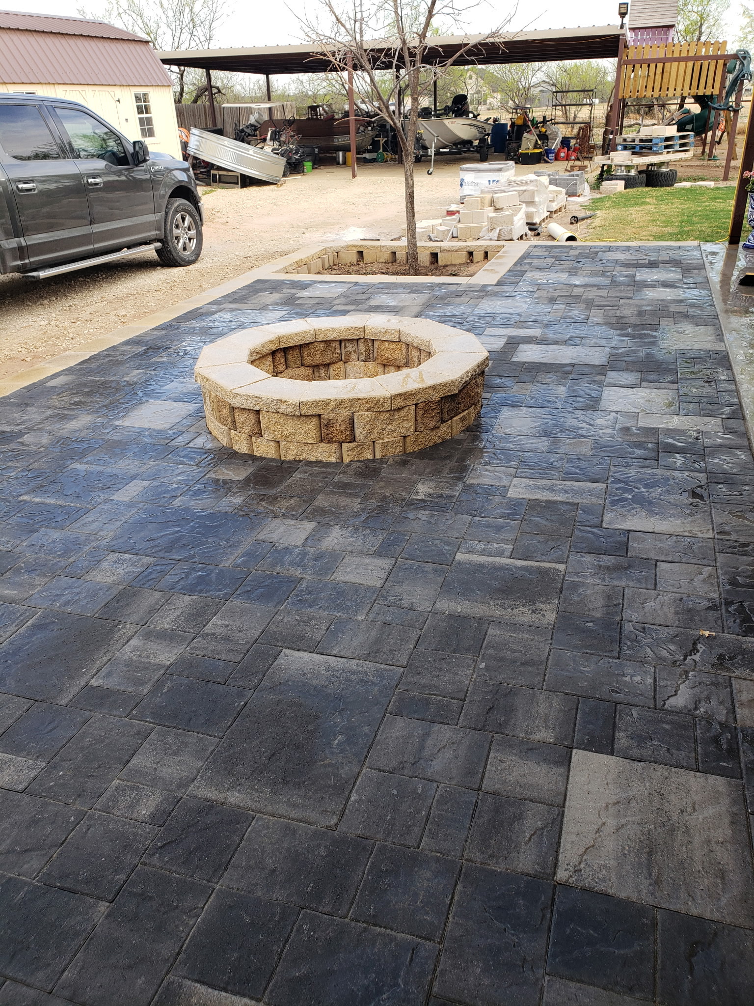 installed paver patio with built-in stone fire pit