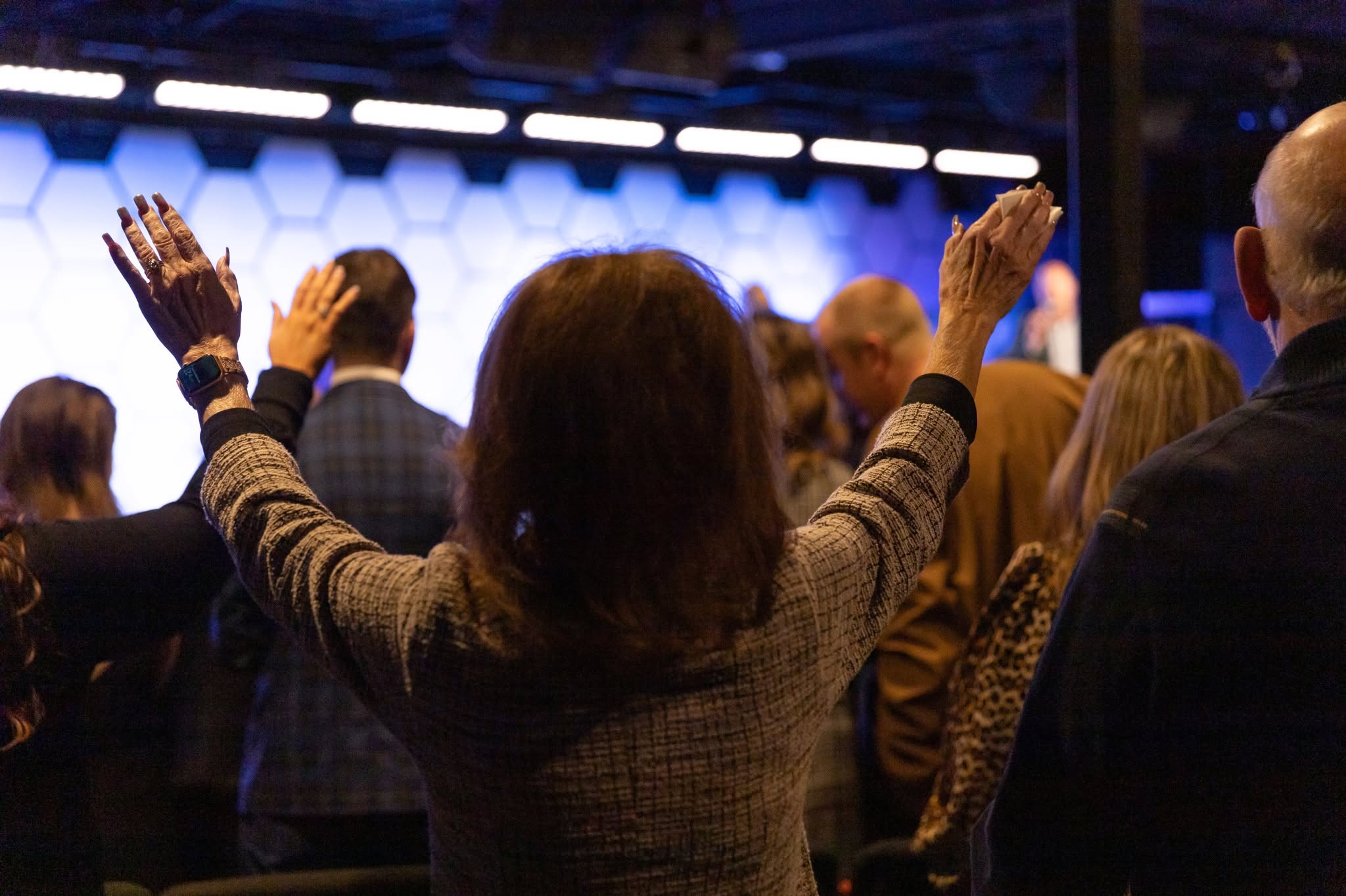Older believer raising hands toward the stage in worship