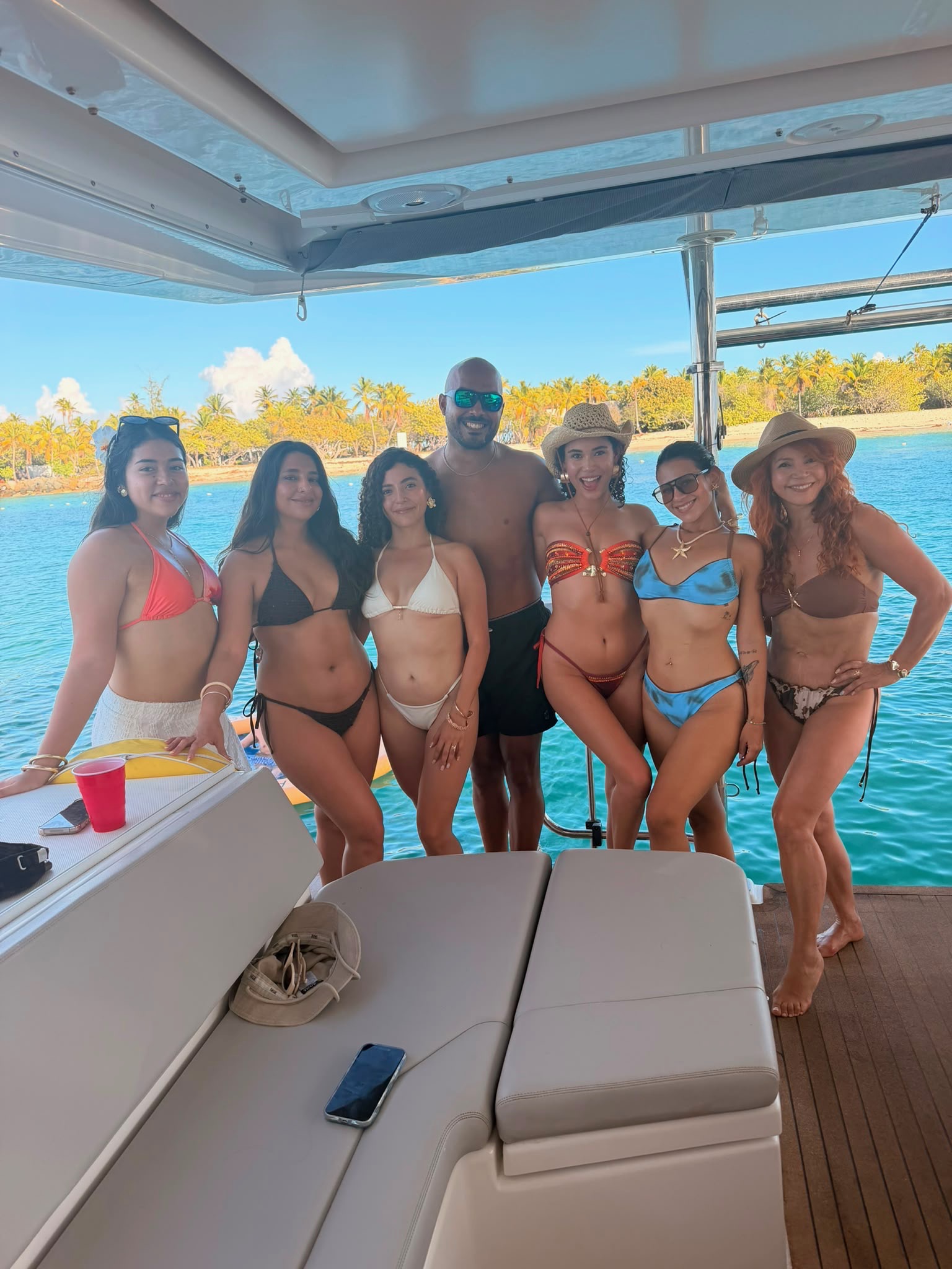 Guests aboard the catamaran — six women and one man enjoying the day on the water