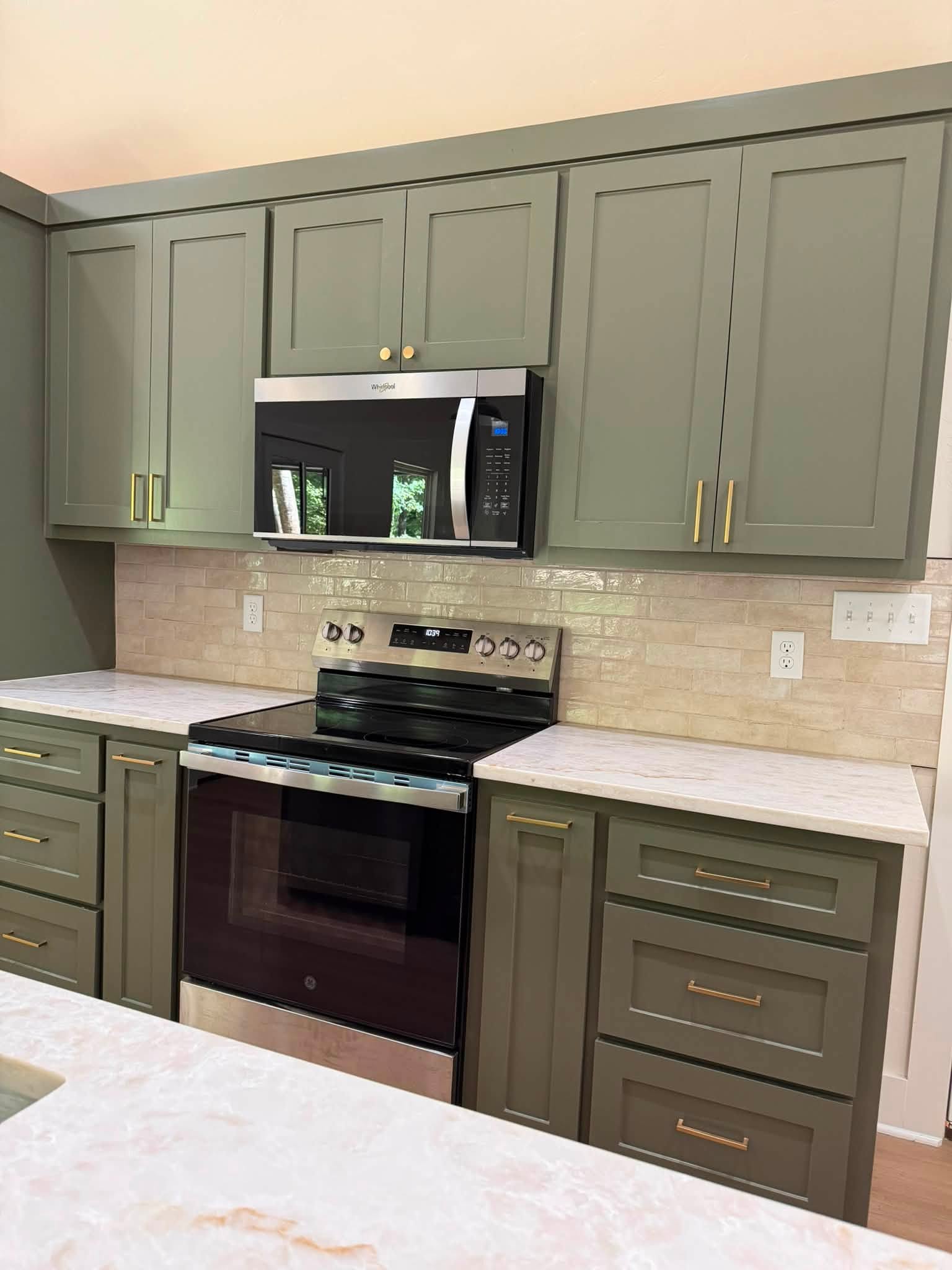 JR Works custom sage kitchen cabinetry, polished stone countertops, and tile backsplash