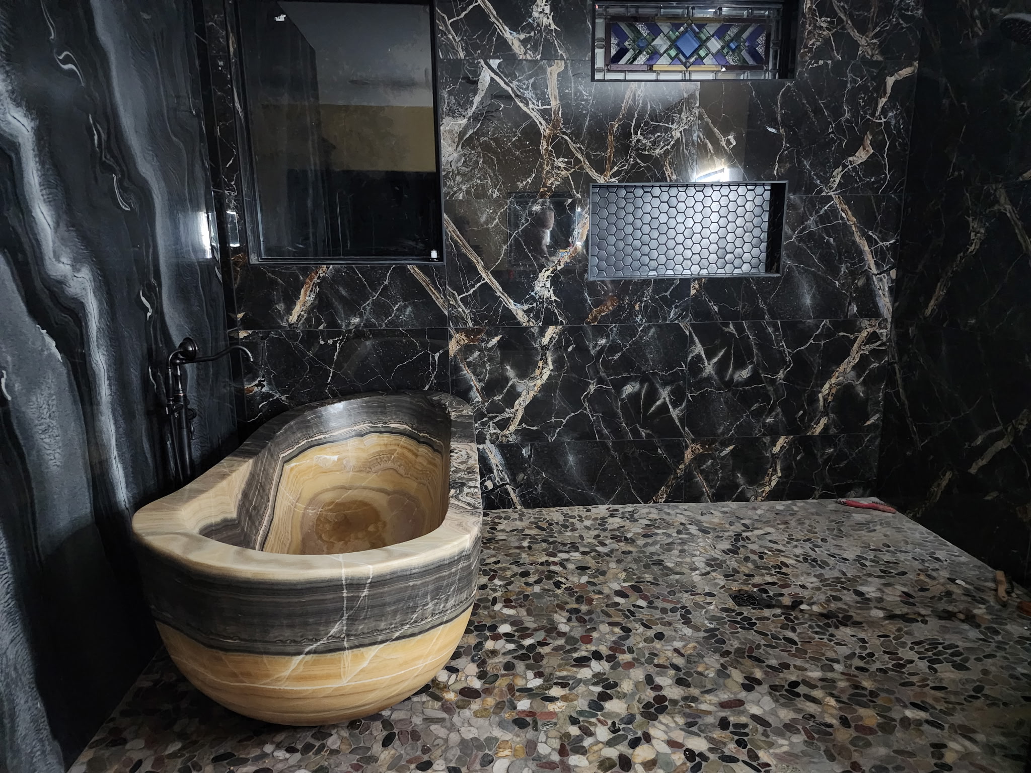 JR Works custom carved stone tub, black marble tile, and luxury bath remodel in East Texas