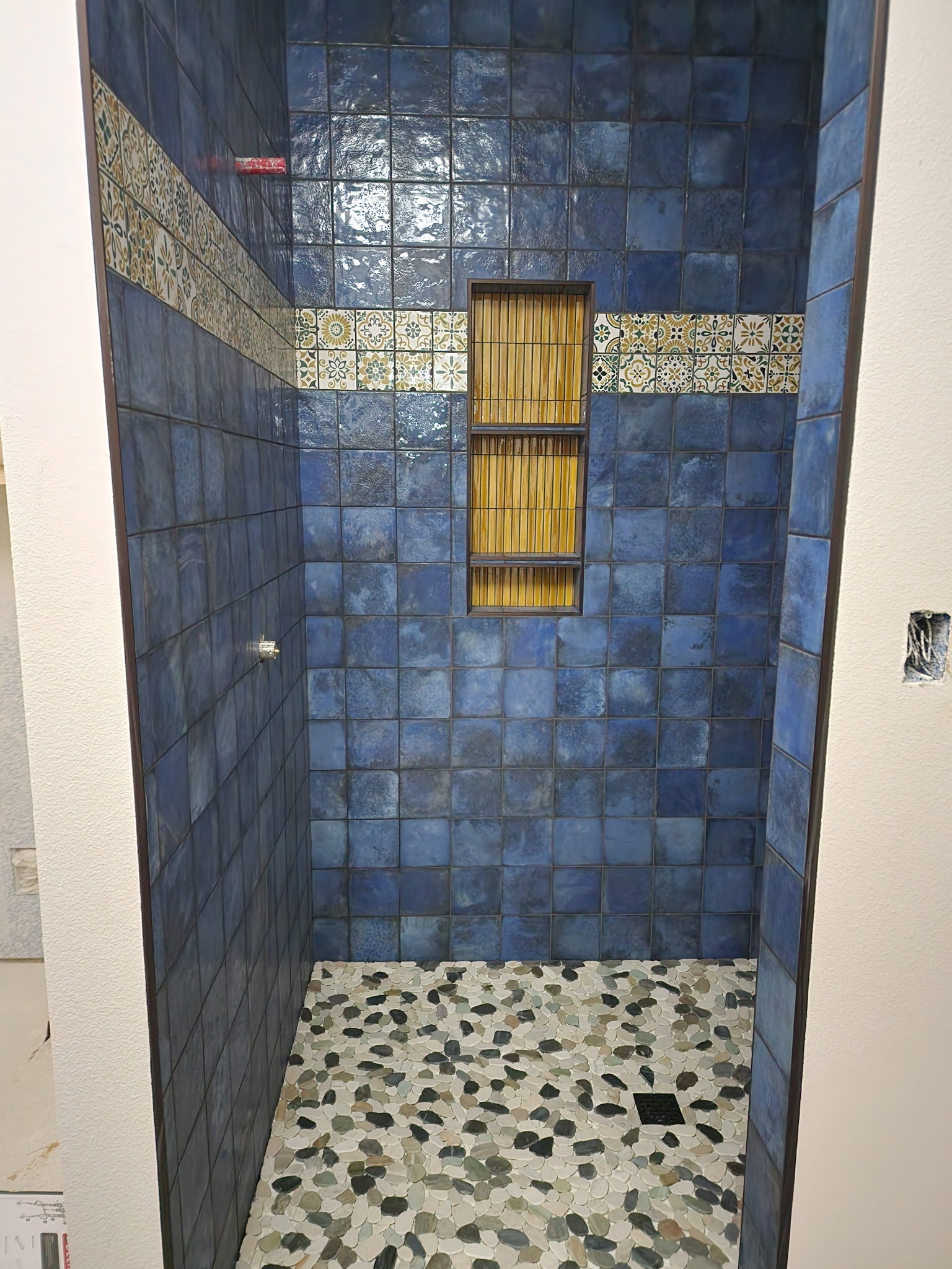 JR Works handcrafted cobalt blue shower tile with mosaic accent band and river rock floor