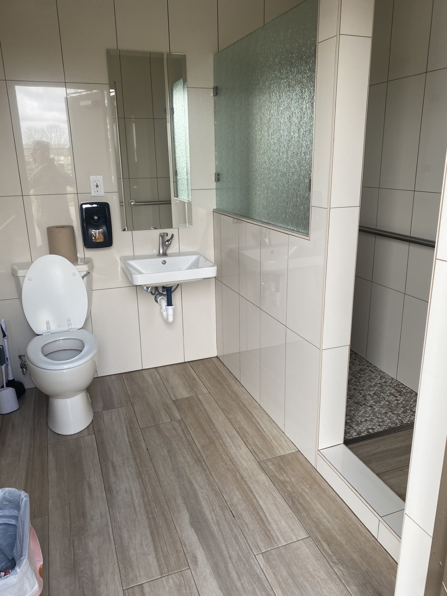 JR Works curb-less walk-in shower with large-format porcelain tile and pebble floor