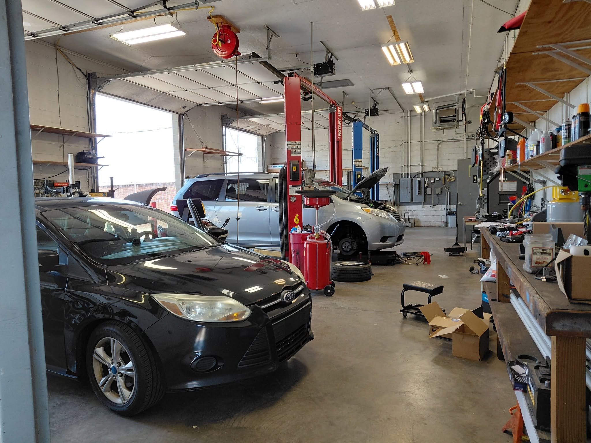 Active vehicle repair bay at Revived Automotive with customer vehicles and equipment