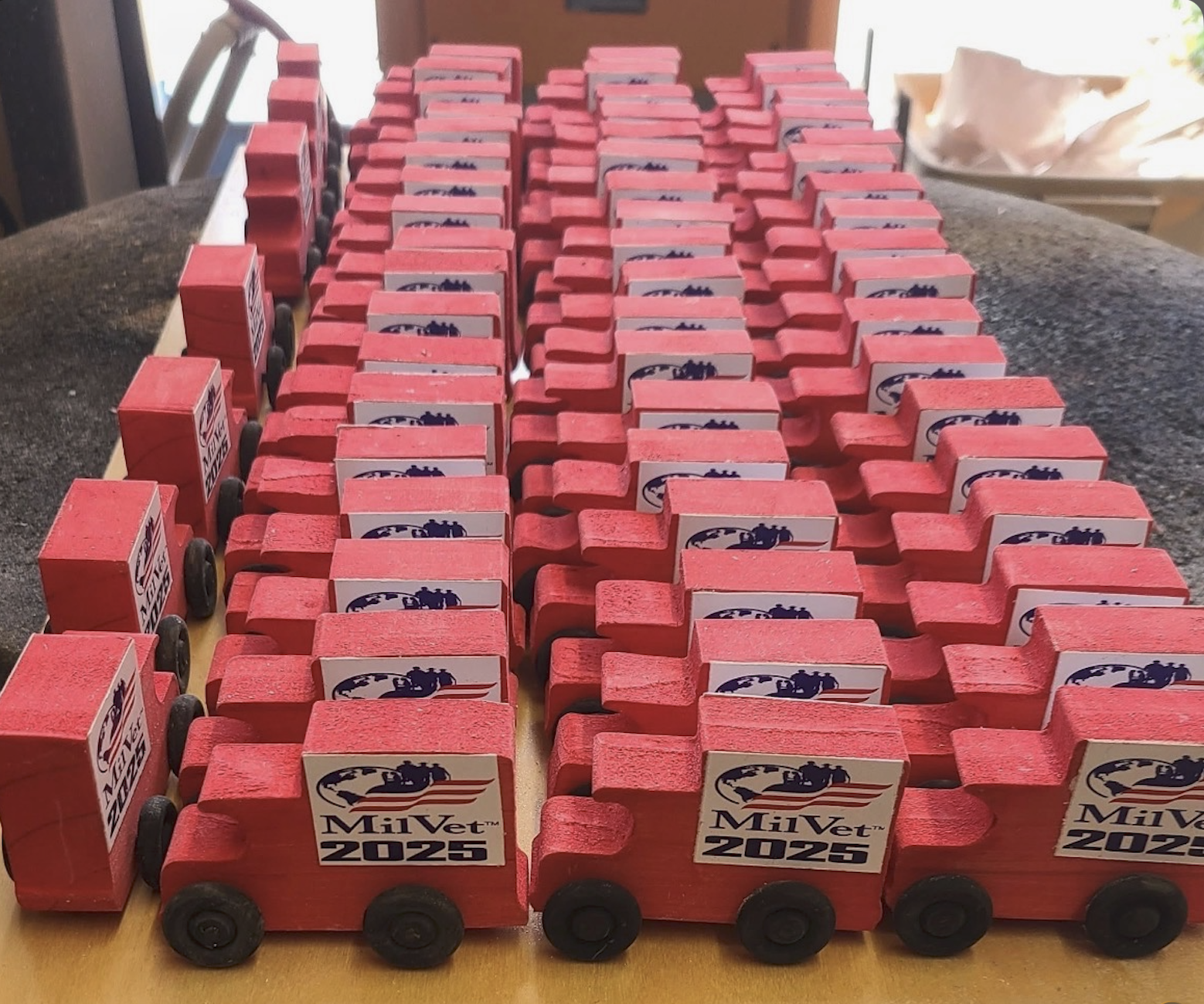 Fleet of handmade red MilVet 2025 toy trucks for veterans and families