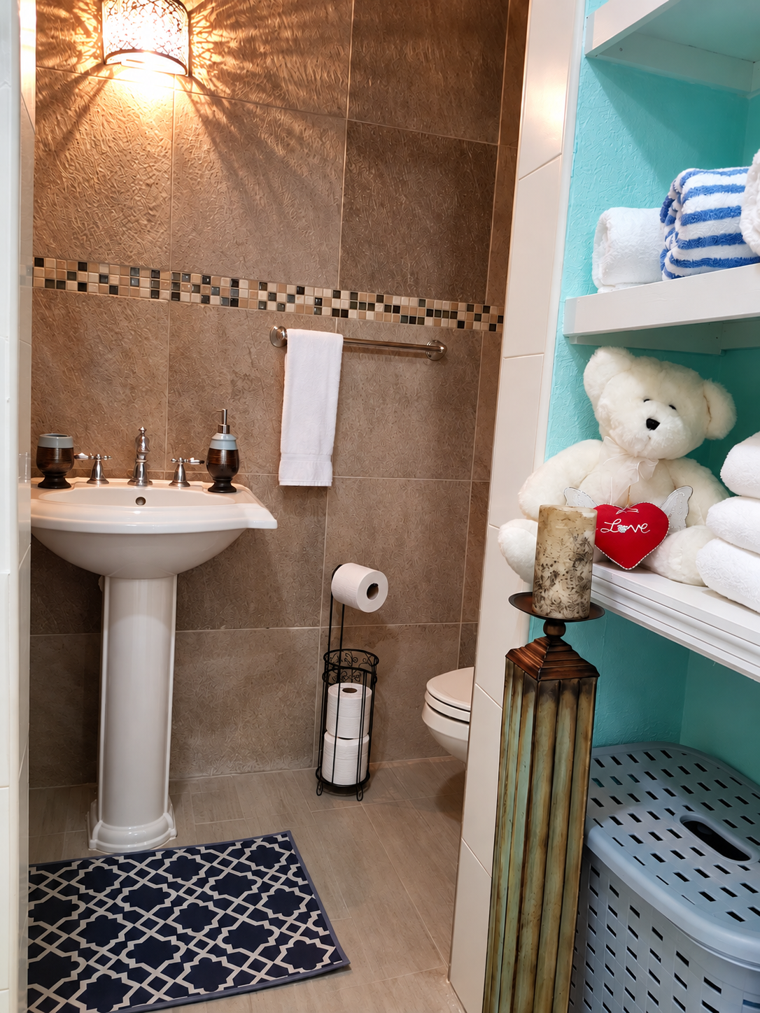 Bathroom with pedestal sink, warm tile accents, and plush towel shelving