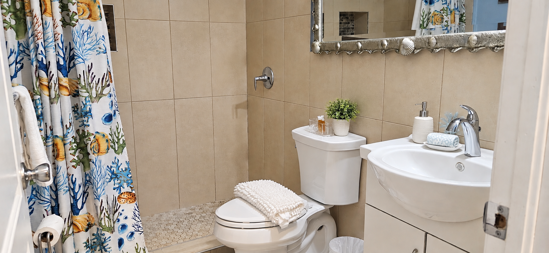 Full bathroom with seashell-framed mirror, white vanity, and walk-in shower