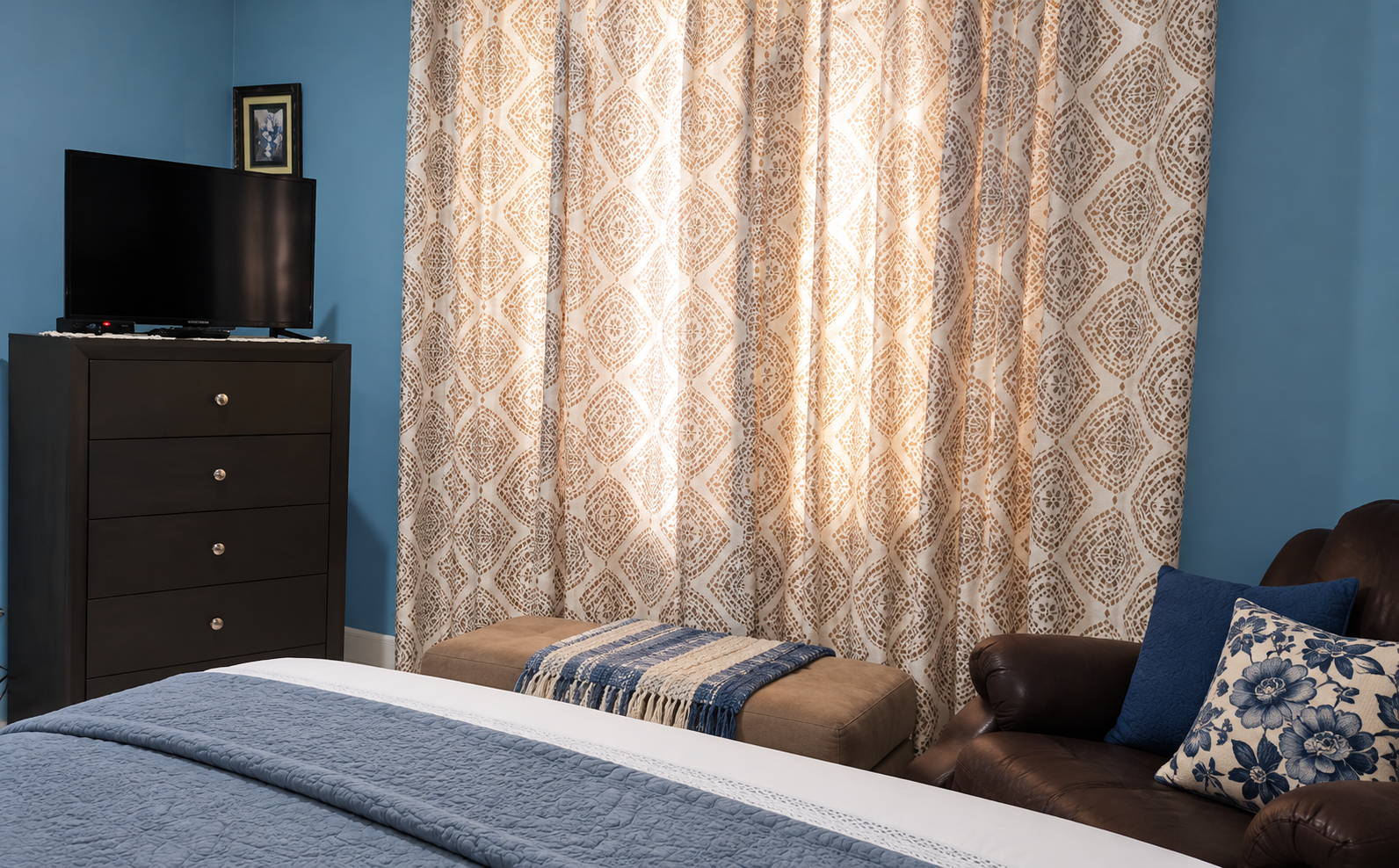 Bedroom seating corner with TV, dresser, and comfortable armchair