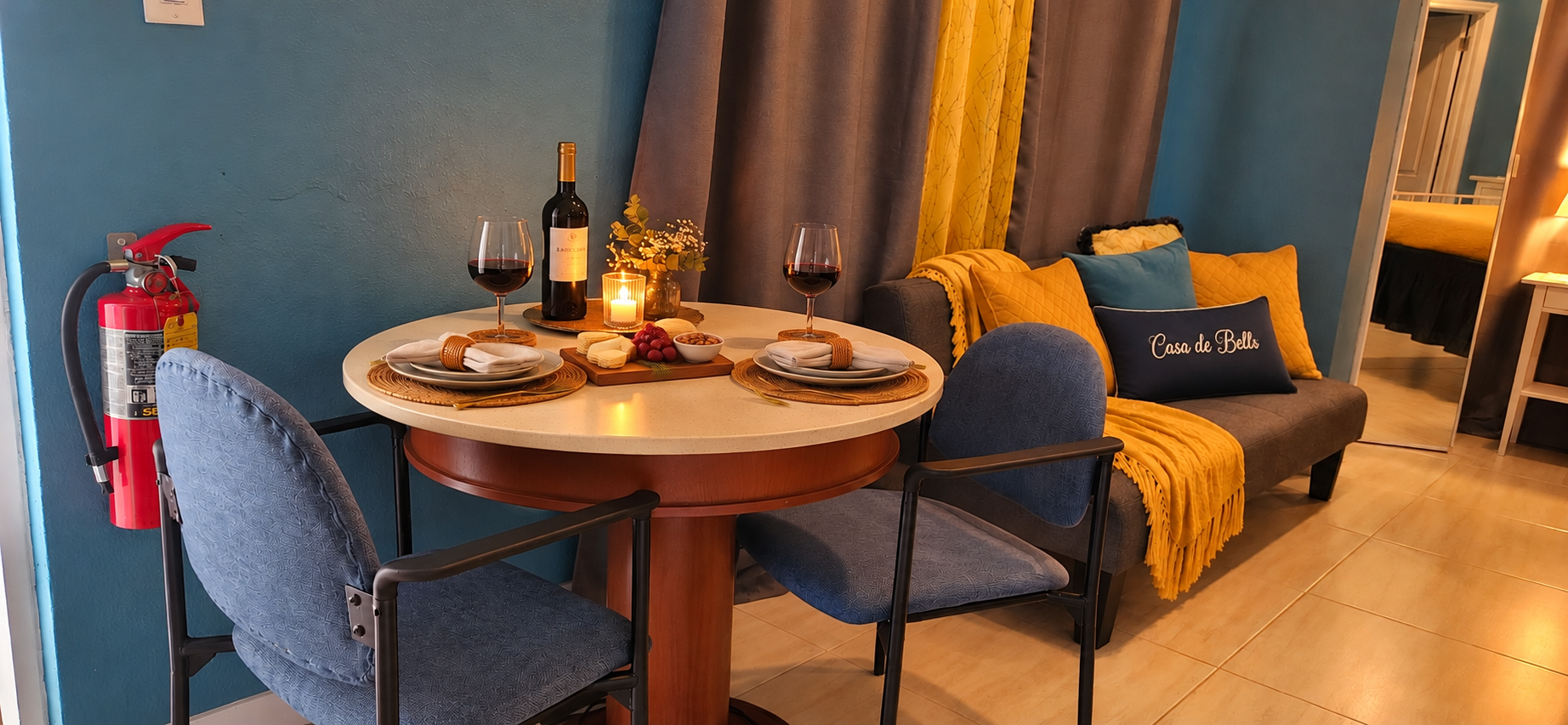 Dining table set for wine and refreshments beside cozy sofa seating