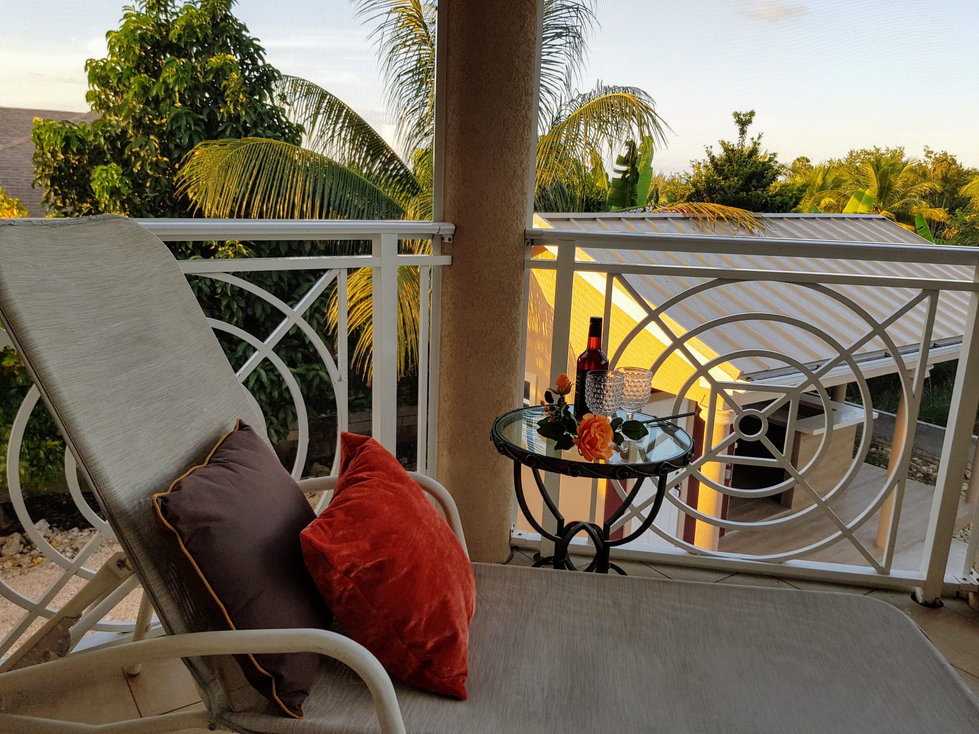 Private covered balcony lounge with sunset views over tropical palms