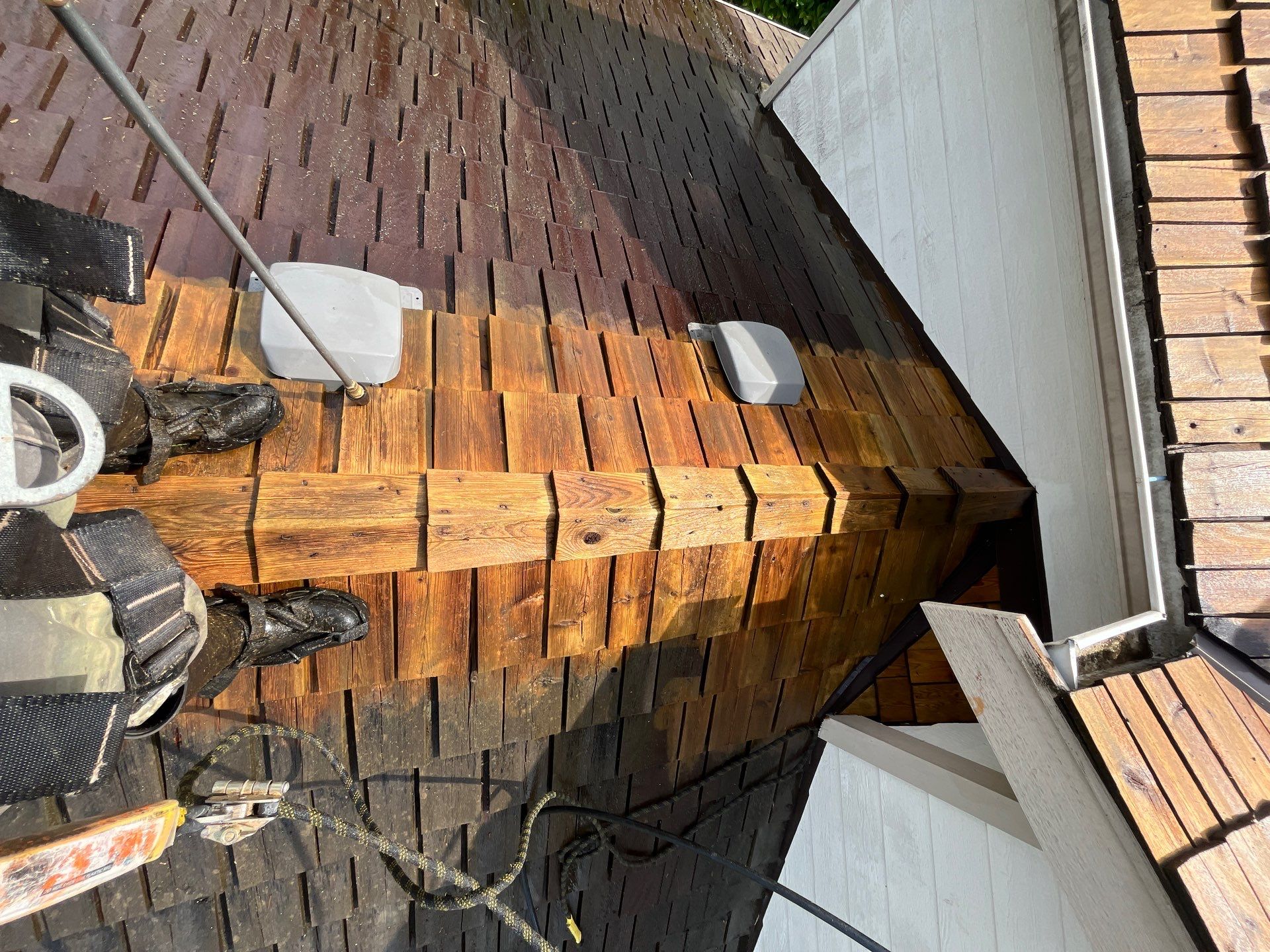 In-progress cedar shake ridge cleaning showing striking contrast between aged dark wood and freshly washed cedar