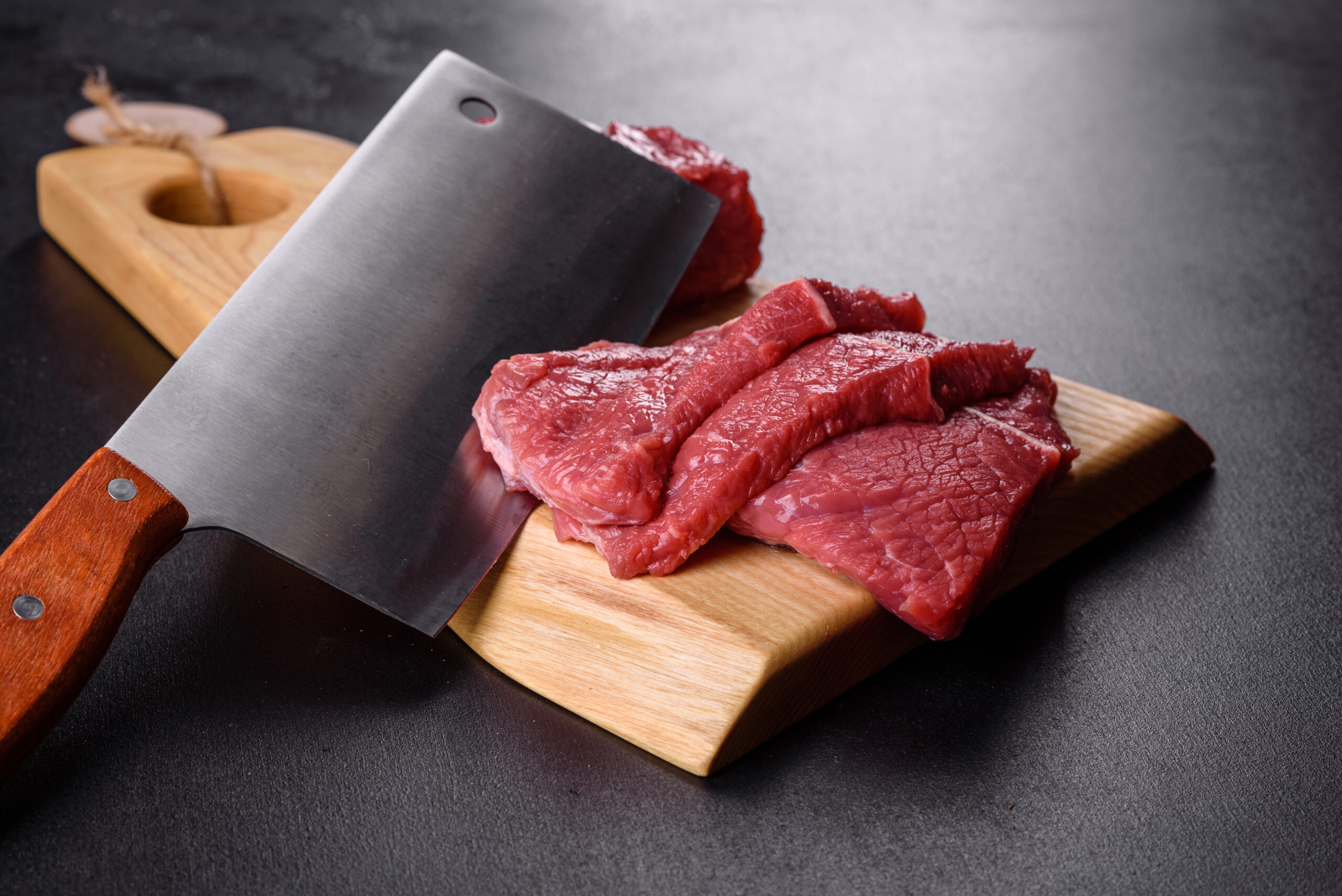 Fresh prepared meat cuts on butcher block with cleaver