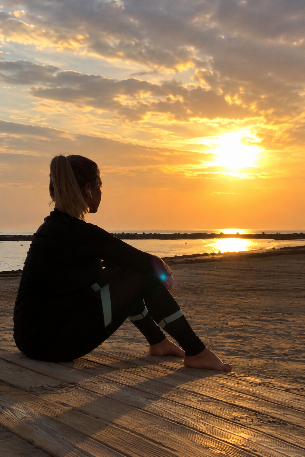 Jennifer Beck sitzend am Meer bei Sonnenuntergang