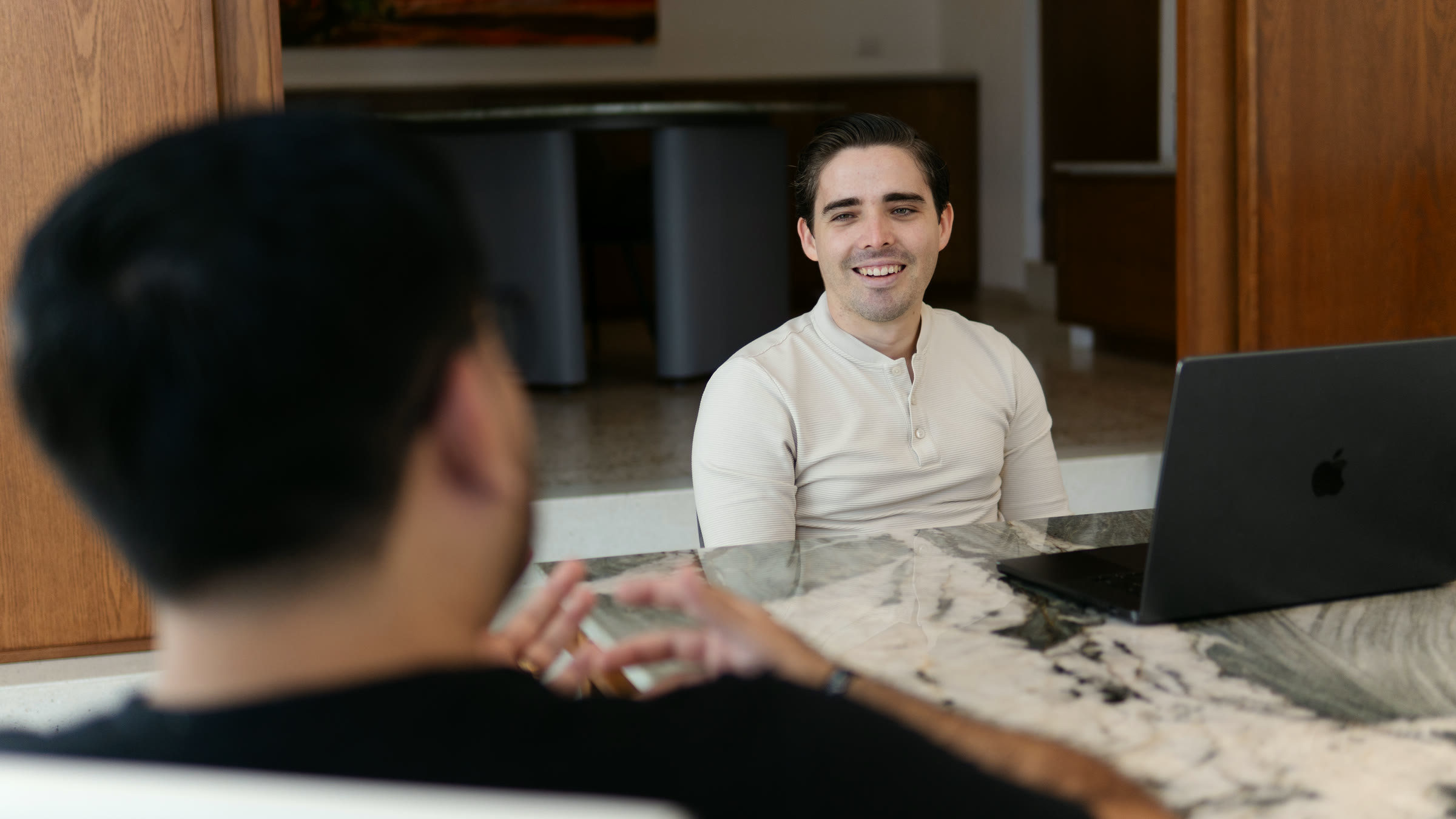 Oswaldo Avilés sentado a la mesa, sonriendo, frente a la persona que le hace una pregunta