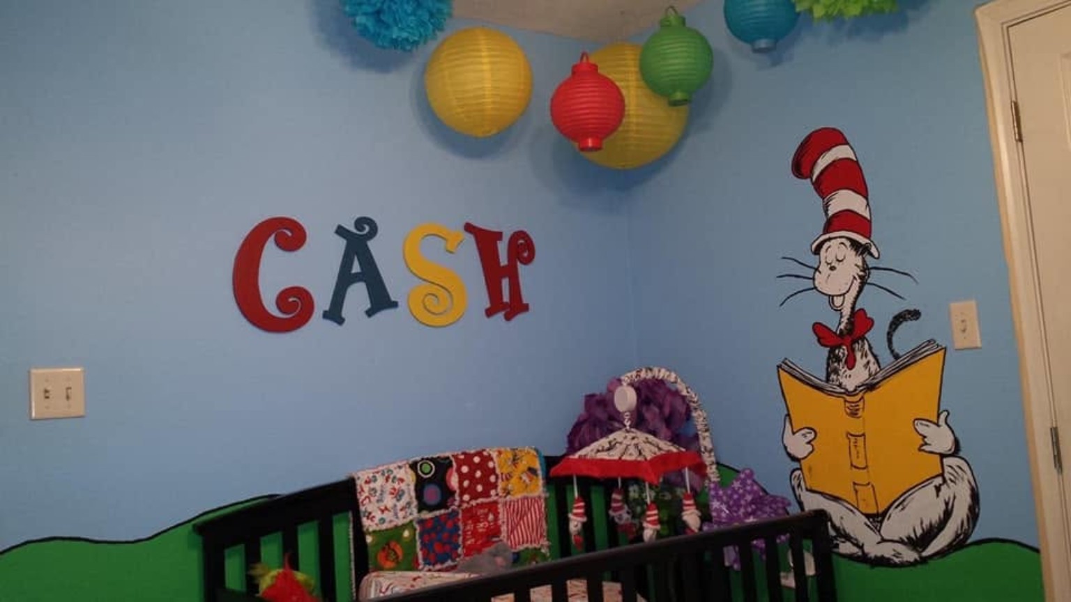 Dr. Seuss themed nursery with Cat in the Hat reading mural, custom Cash lettering, crib, and hanging lanterns