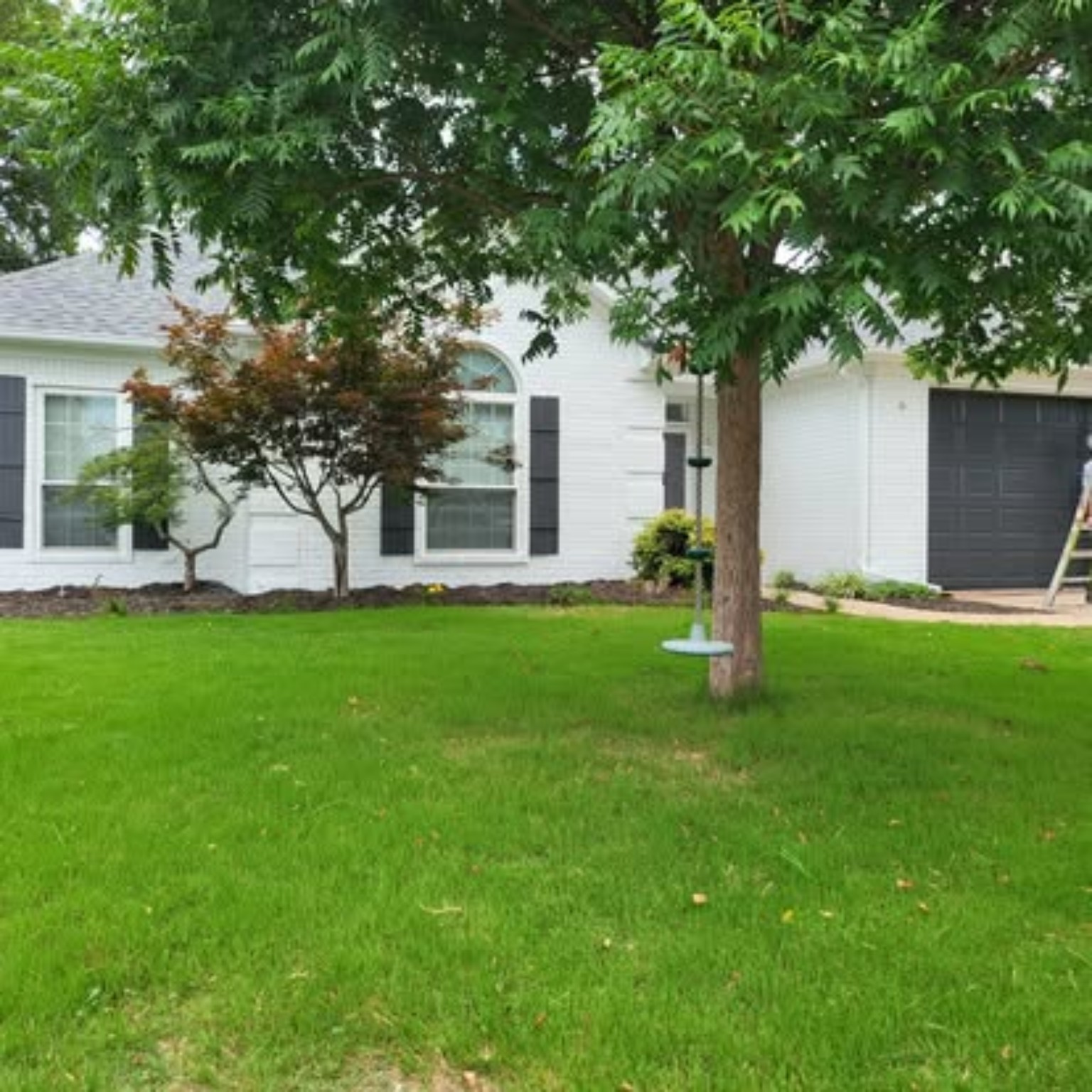 Completed white painted brick home with dark shutters and black garage door
