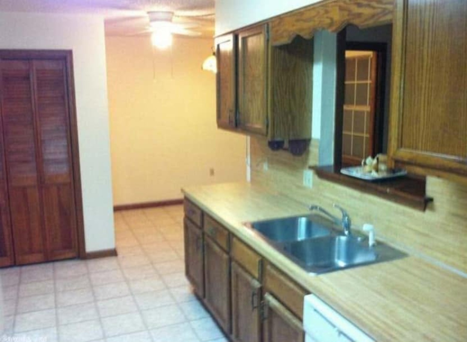 Original galley kitchen before renovation with oak cabinets, laminate countertops, and linoleum flooring