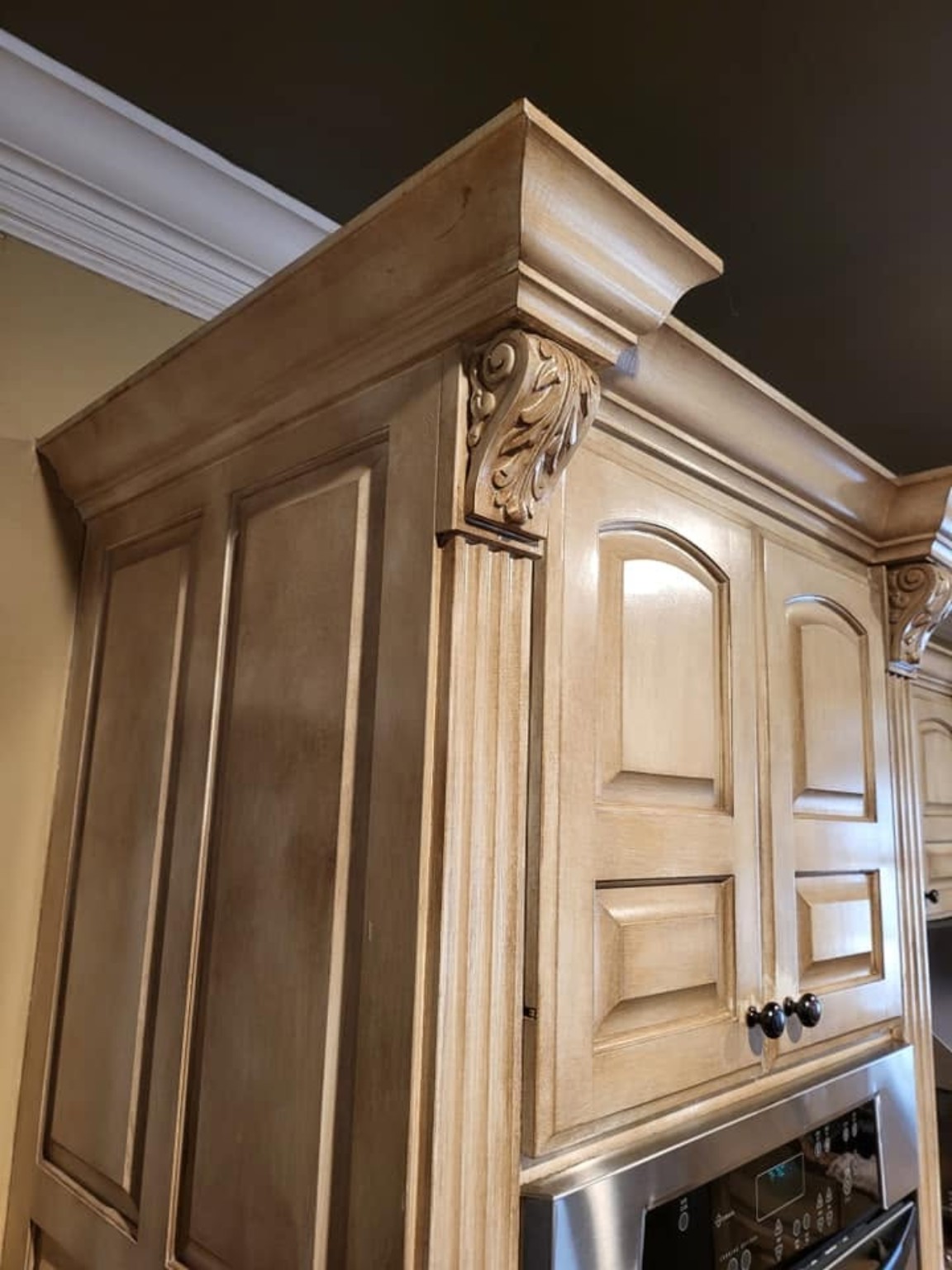 Decorative glazed finish on custom cabinetry crown molding, carved corbel, and upper cabinet doors