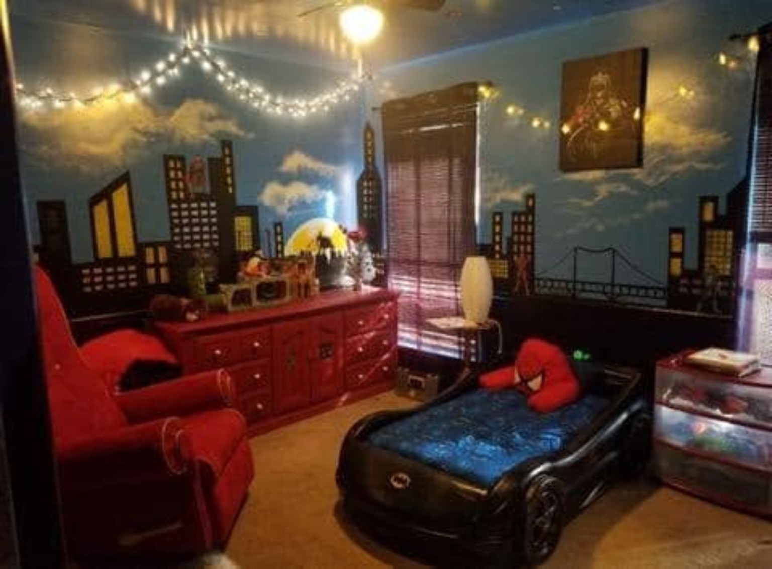 Superhero bedroom with city skyline mural, suspension bridge, string lights, and racecar bed