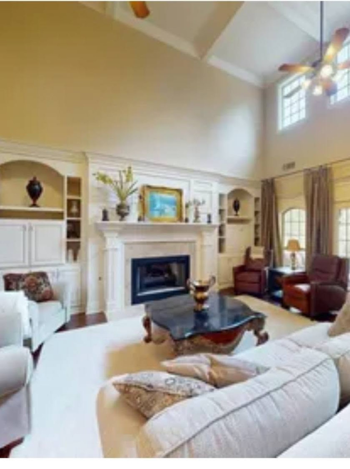 Living room and high-ceiling built-in fireplace before painting - original light cream wood finish