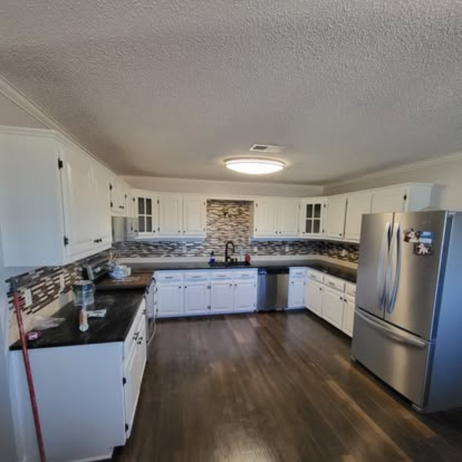 Full kitchen completed transformation with crisp white cabinetry, dark countertops, and stainless appliances