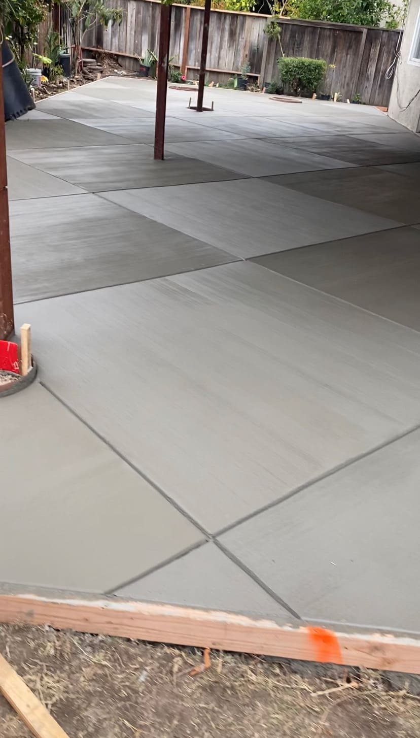 Large residential concrete patio with alternating broom-finished rectangular panels and clean control joints
