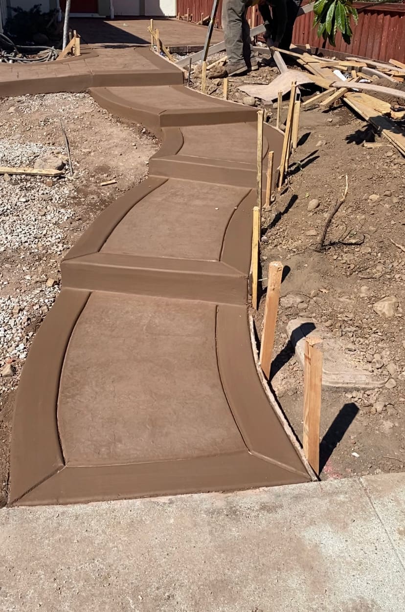 Curved decorative stamped concrete walkway steps with picture frame border under construction