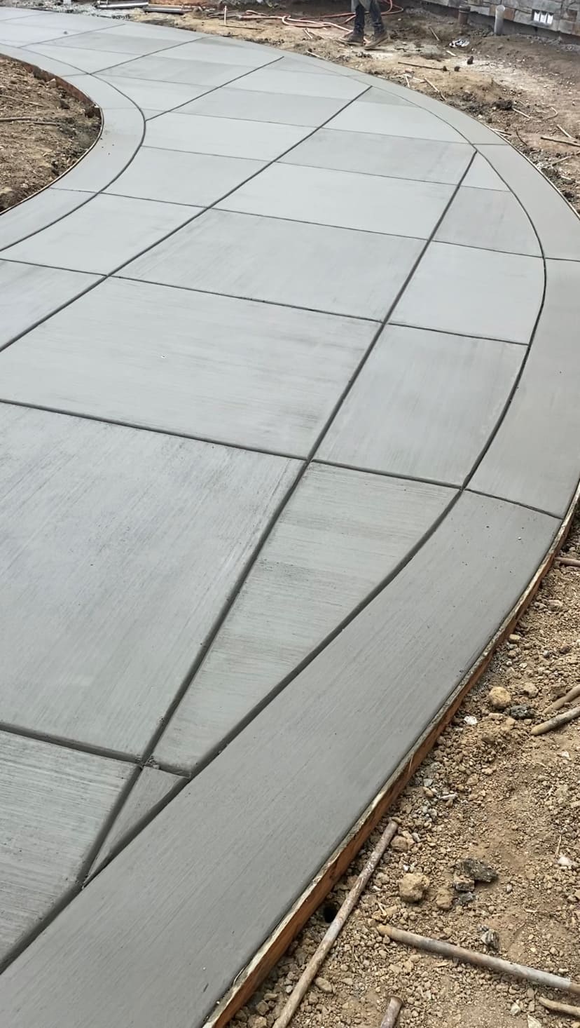Sweeping curved concrete walkway with decorative picture frame troweled border and broom finish