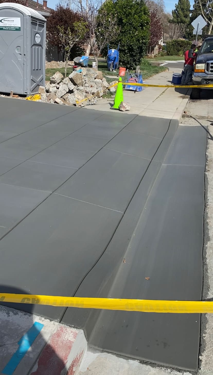 Freshly poured concrete driveway with clean broom finish and custom rolled curb transition
