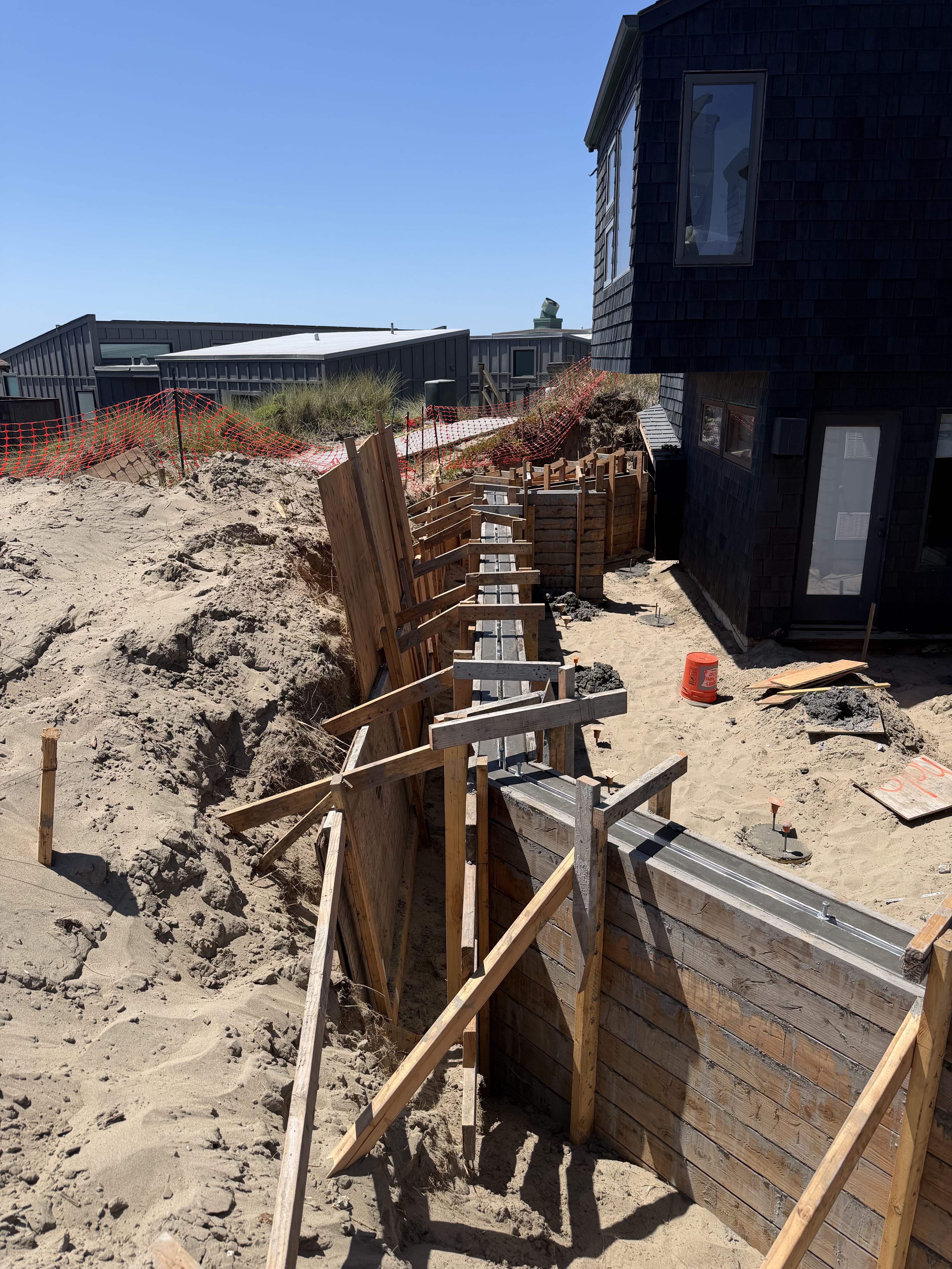Stepped concrete retaining wall forms and structural framing along a hillside residential property