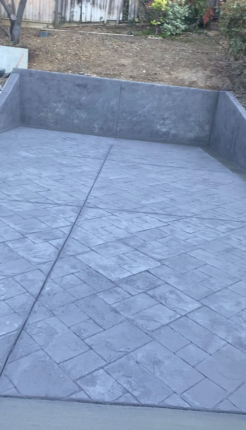 Ashlar slate stamped concrete patio pad integrated with textured concrete retaining walls