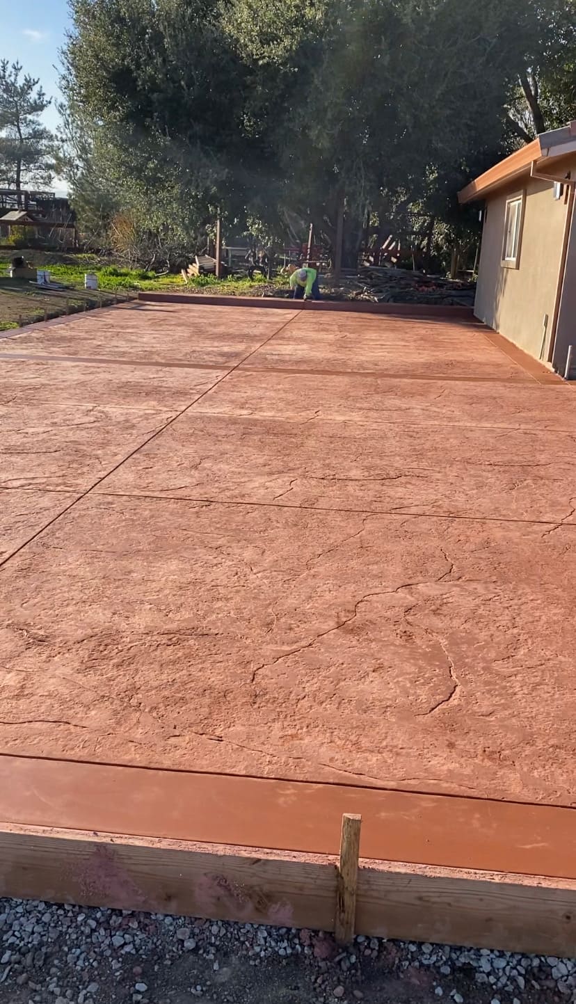 Large stamped concrete patio with warm earth-tone finish, textured pattern, and borders