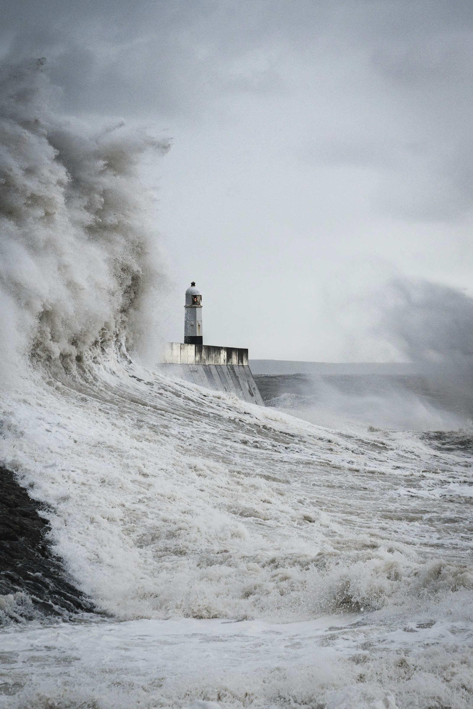 Lighthouse standing firm against a massive crashing wave in a storm, representing attraction-based marketing