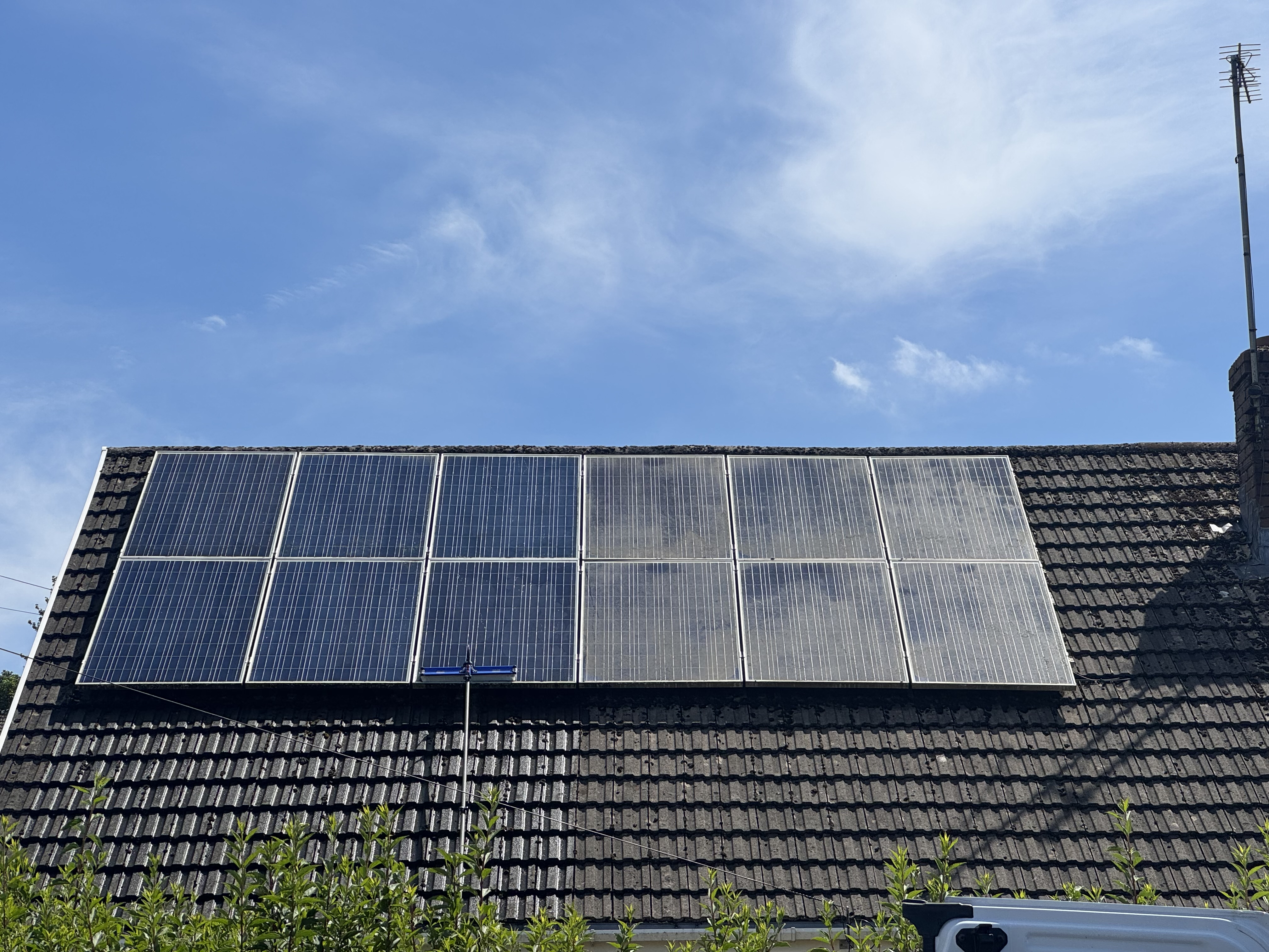 Residential rooftop solar array during cleaning with telescopic reach pole from ground level