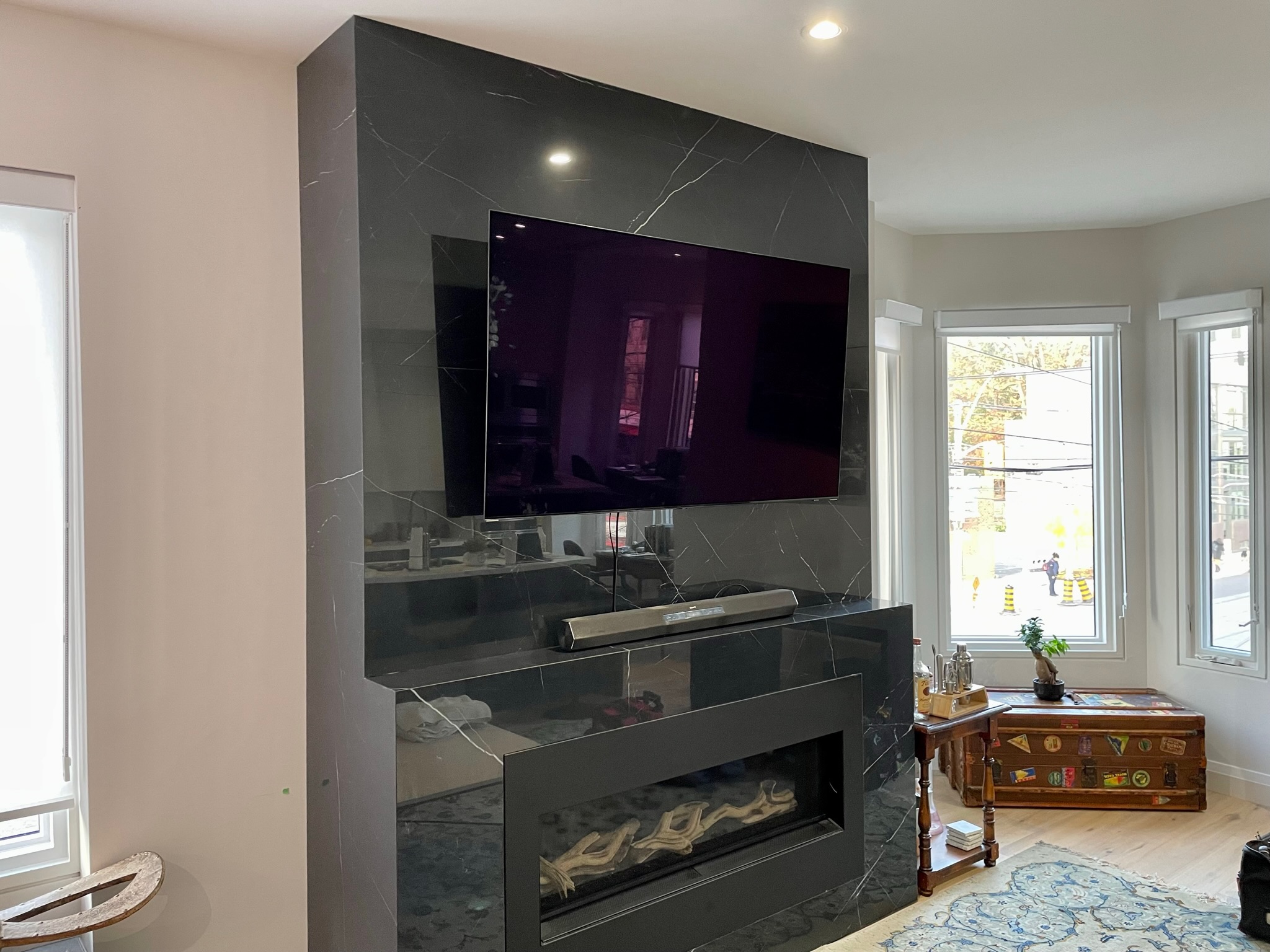 Mount Masters luxury black marble porcelain slab fireplace TV installation with soundbar and modern linear hearth