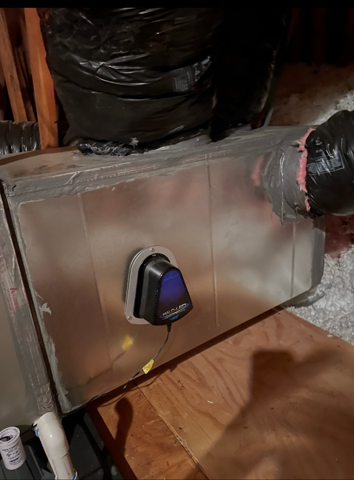 Cadillac Heating & Air technician inspecting ductwork in an attic