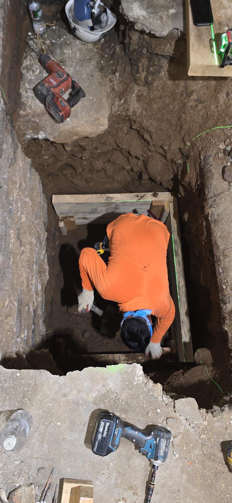 Craftsman securing structural timber forms in deep foundation pit with laser level by LQJ General Construction in Central Islip NY