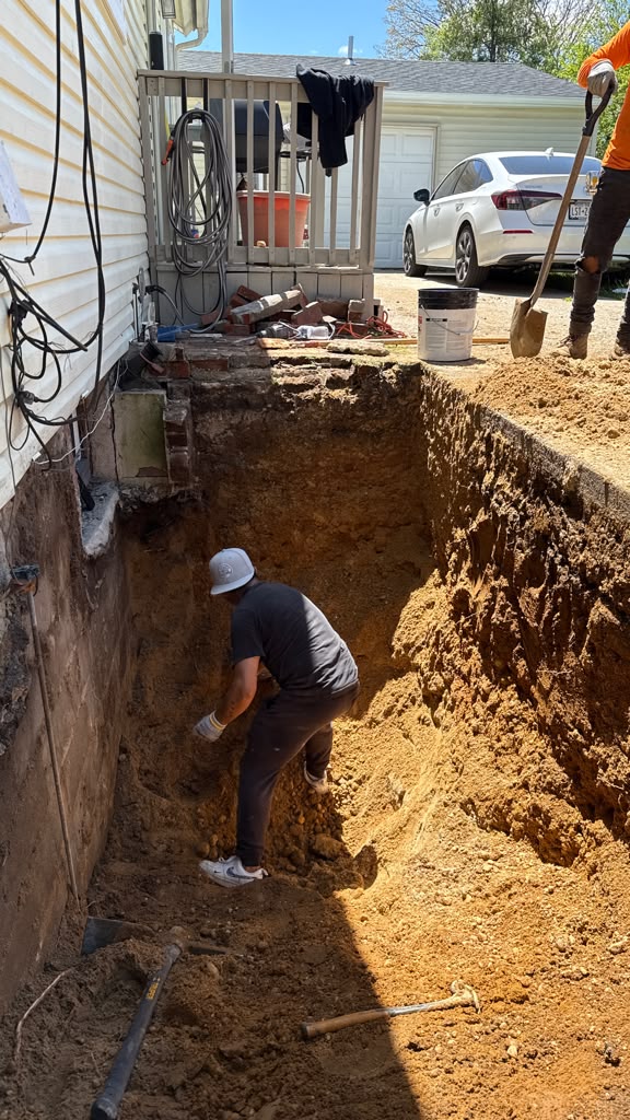 Contractor hand-excavating deep trench for outside basement entrance foundation stairs by LQJ General Construction in Central Islip NY