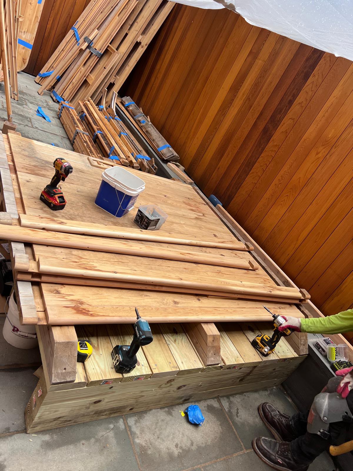 Carpenters securing tongue-and-groove cedar subfloor on pressure-treated deck platform by LQJ General Construction in Northport NY