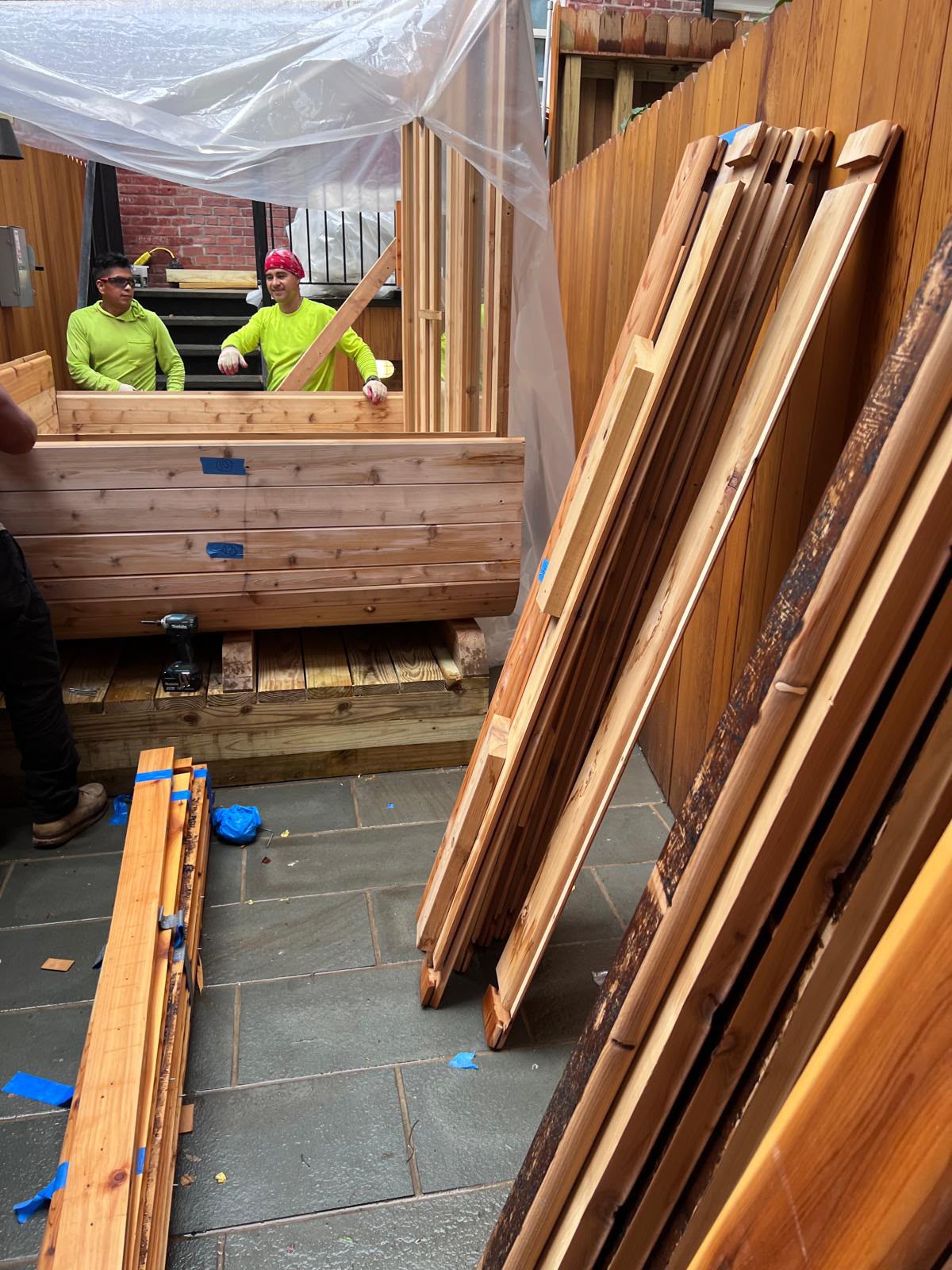 LQJ General Construction carpentry crew staging tongue-and-groove cedar planks and assembling outdoor barrel sauna