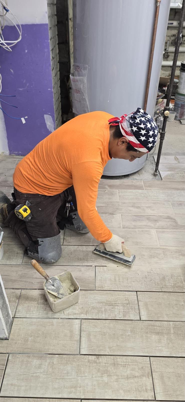 LQJ General Construction craftsman hand-troweling grout across wood-look porcelain tile flooring in Central Islip NY