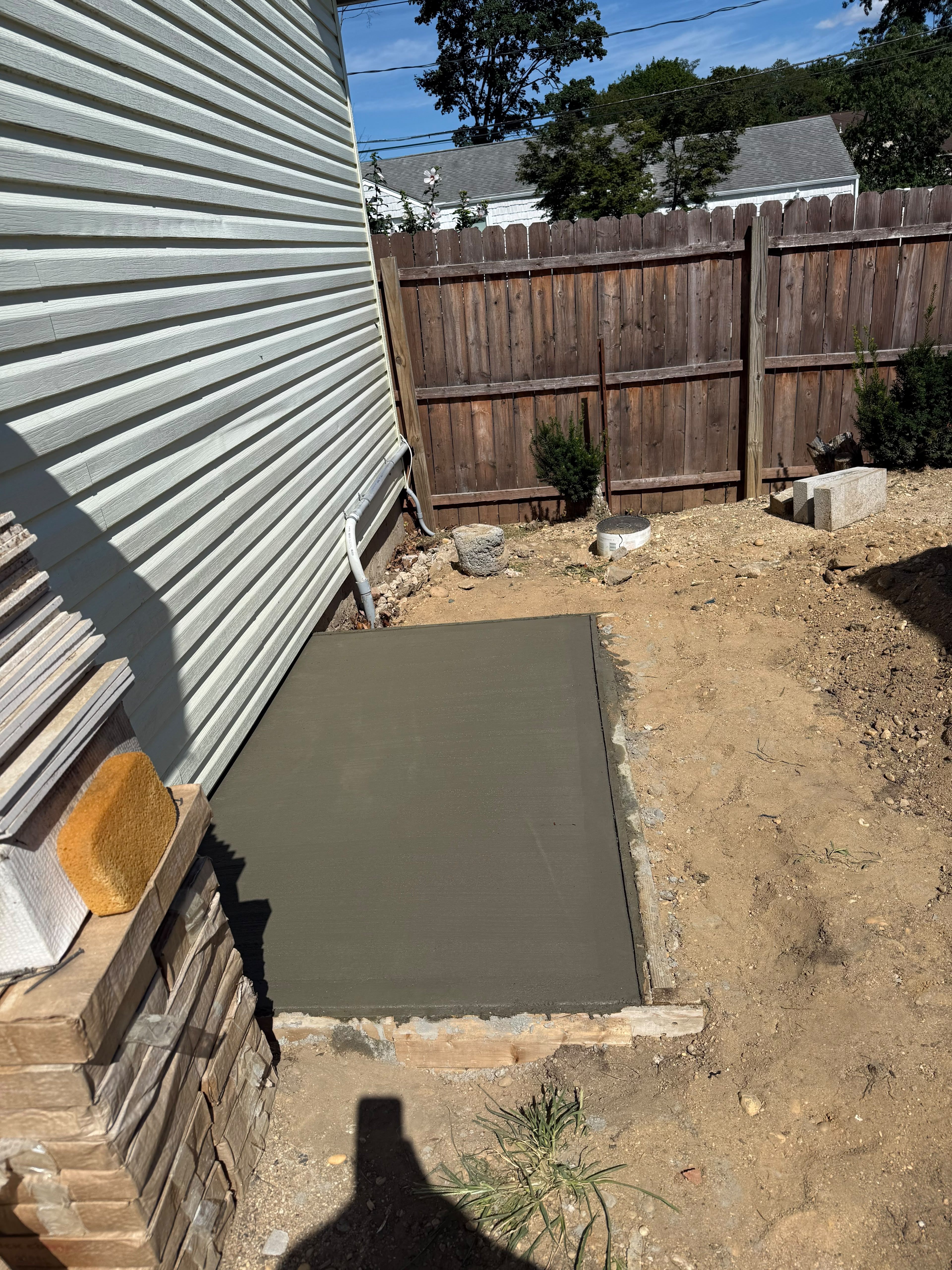Poured and leveled exterior concrete equipment pad along residential siding by LQJ General Construction in Central Islip NY