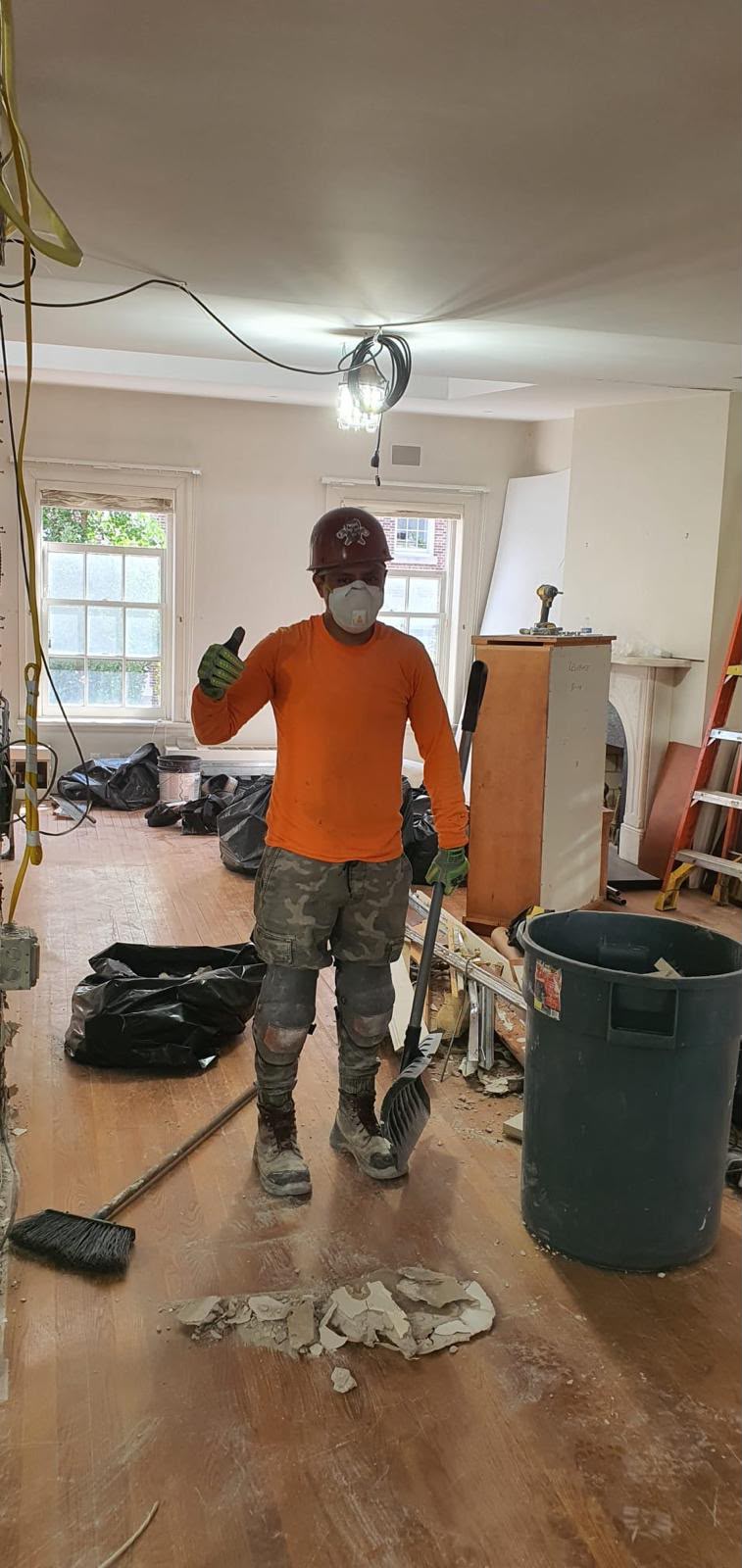 LQJ General Construction team member giving thumbs-up during interior home renovation demolition and daily jobsite sweep