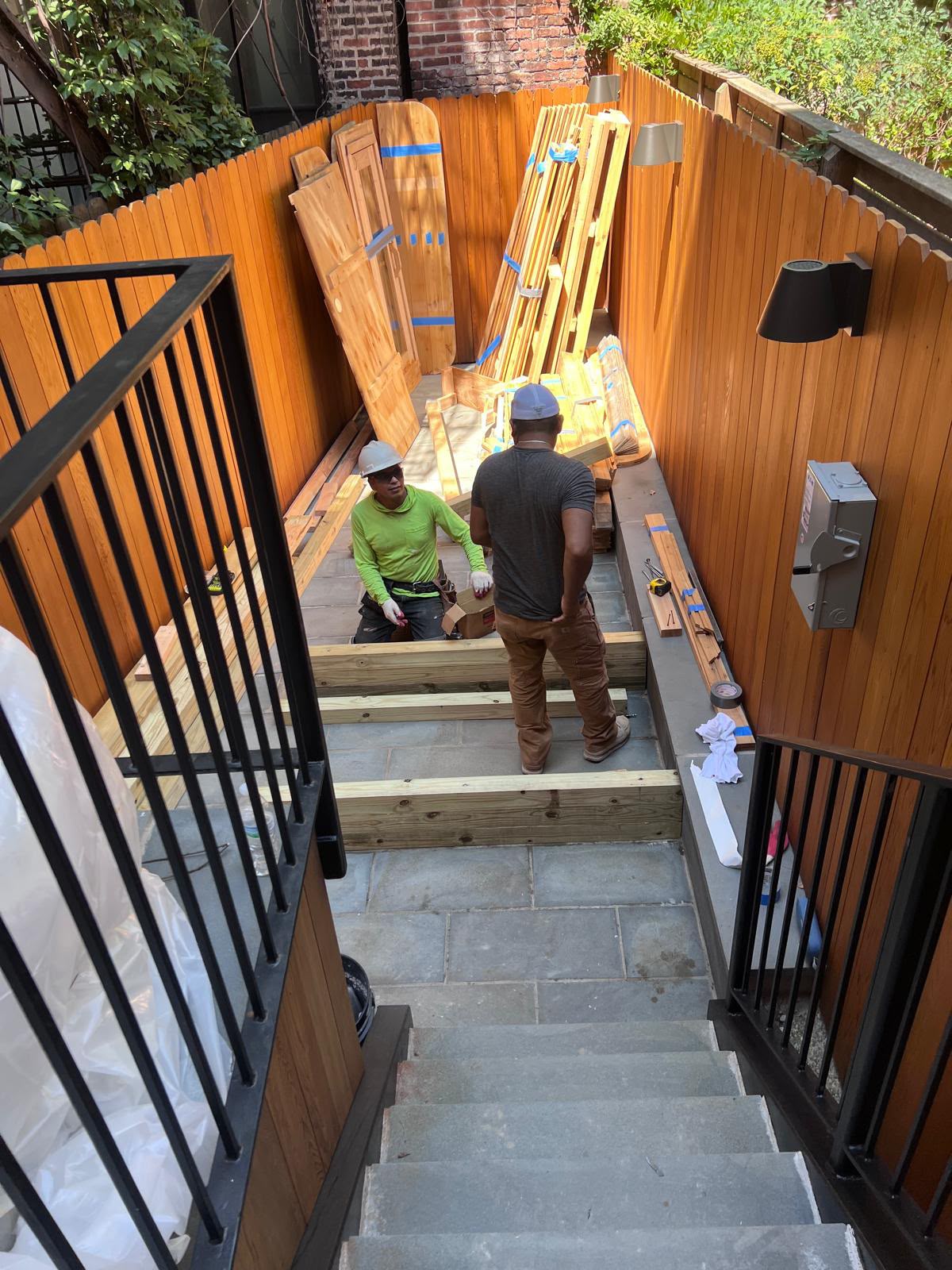 LQJ General Construction carpenters assembling pressure-treated deck framing stairs and cedar fencing in Northport NY