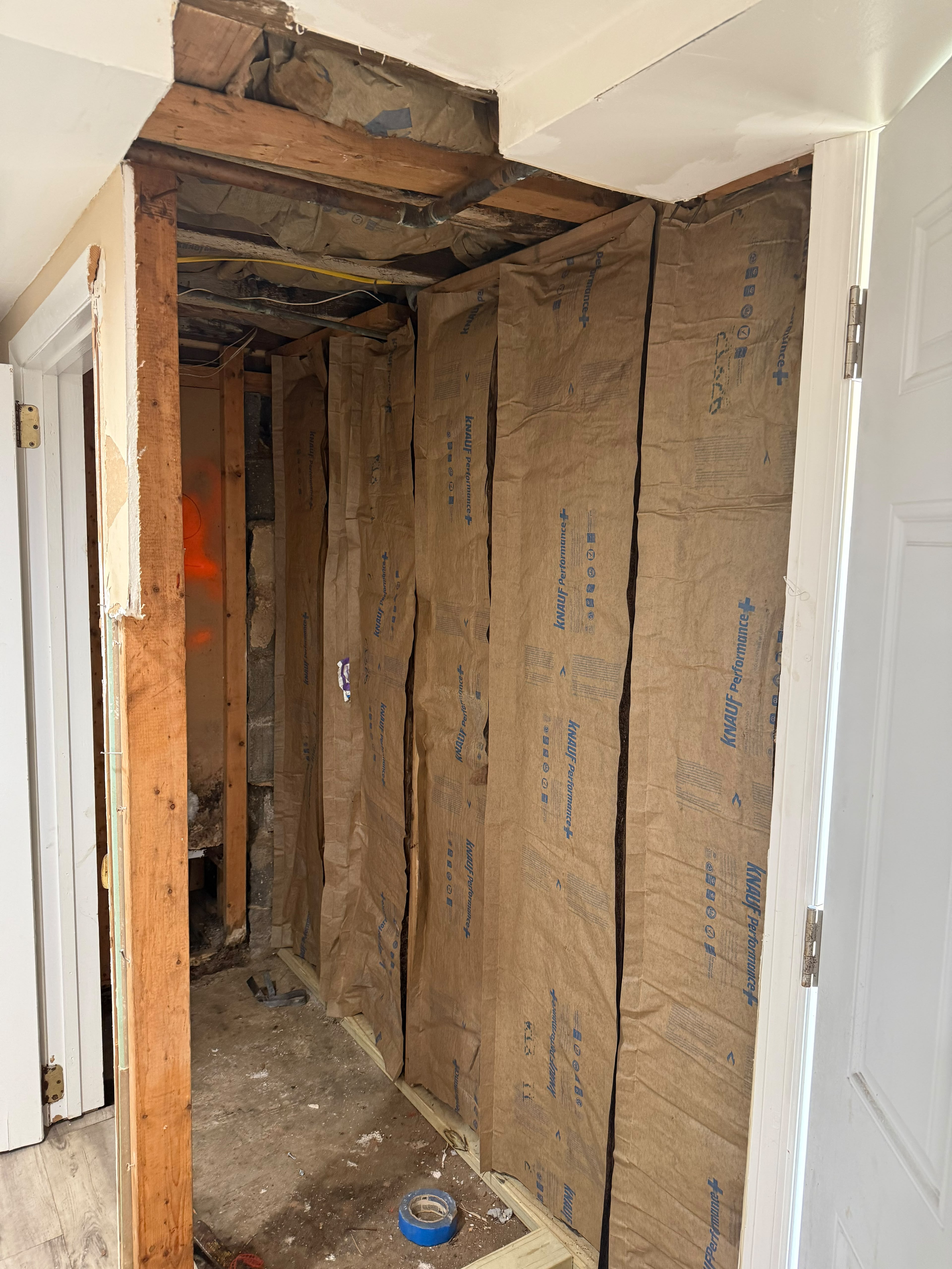 Kraft-faced Knauf Performance fiberglass insulation batts in framed basement wall cavity by LQJ General Construction in Bay Shore NY