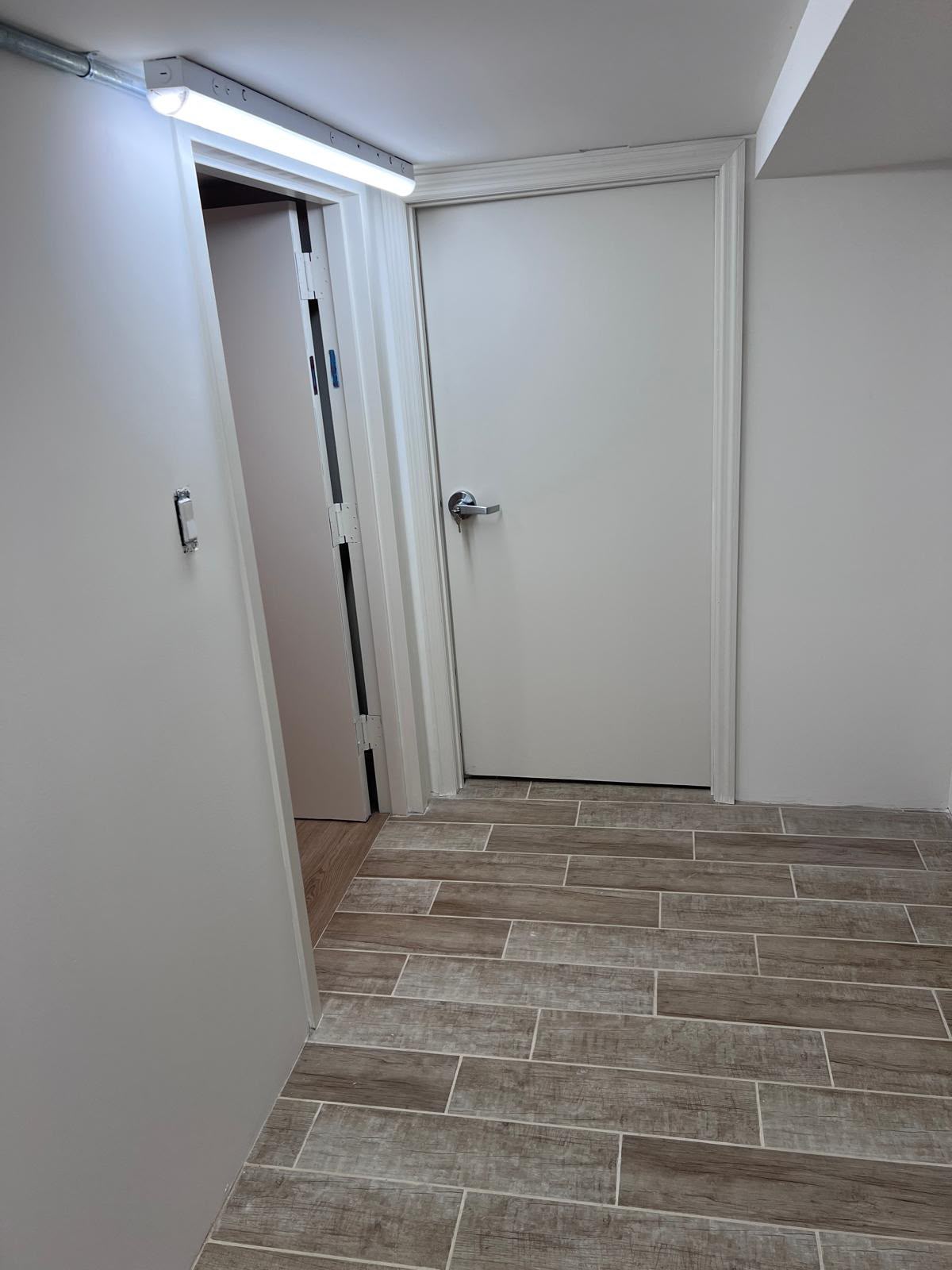 Finished interior passage doors, brushed nickel hardware, and wood-grain porcelain tile floor installed by LQJ General Construction
