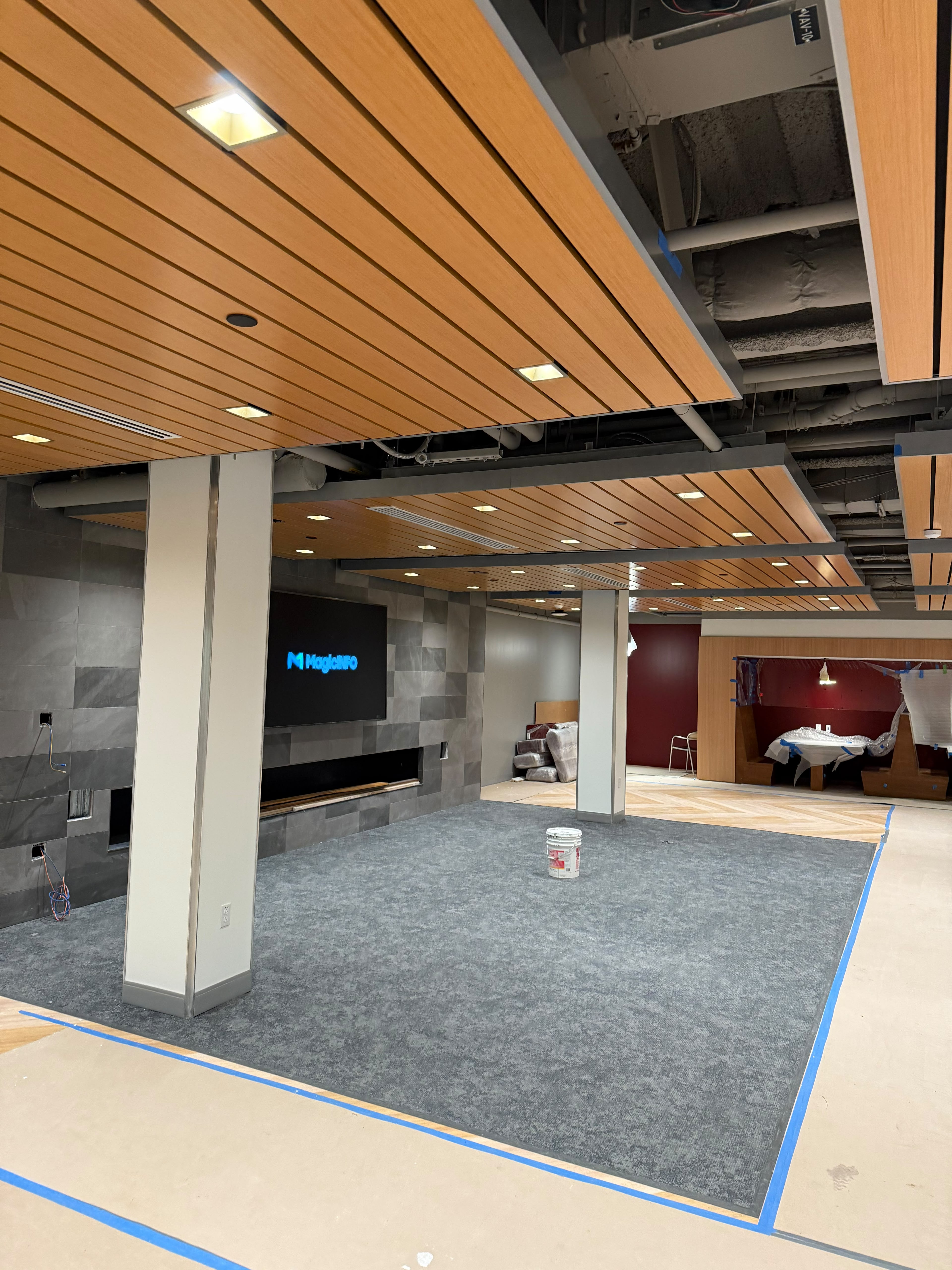 Completed luxury interior lounge renovation with wood slat ceiling clouds, tiled accent wall, and commercial flooring by LQJ General Construction