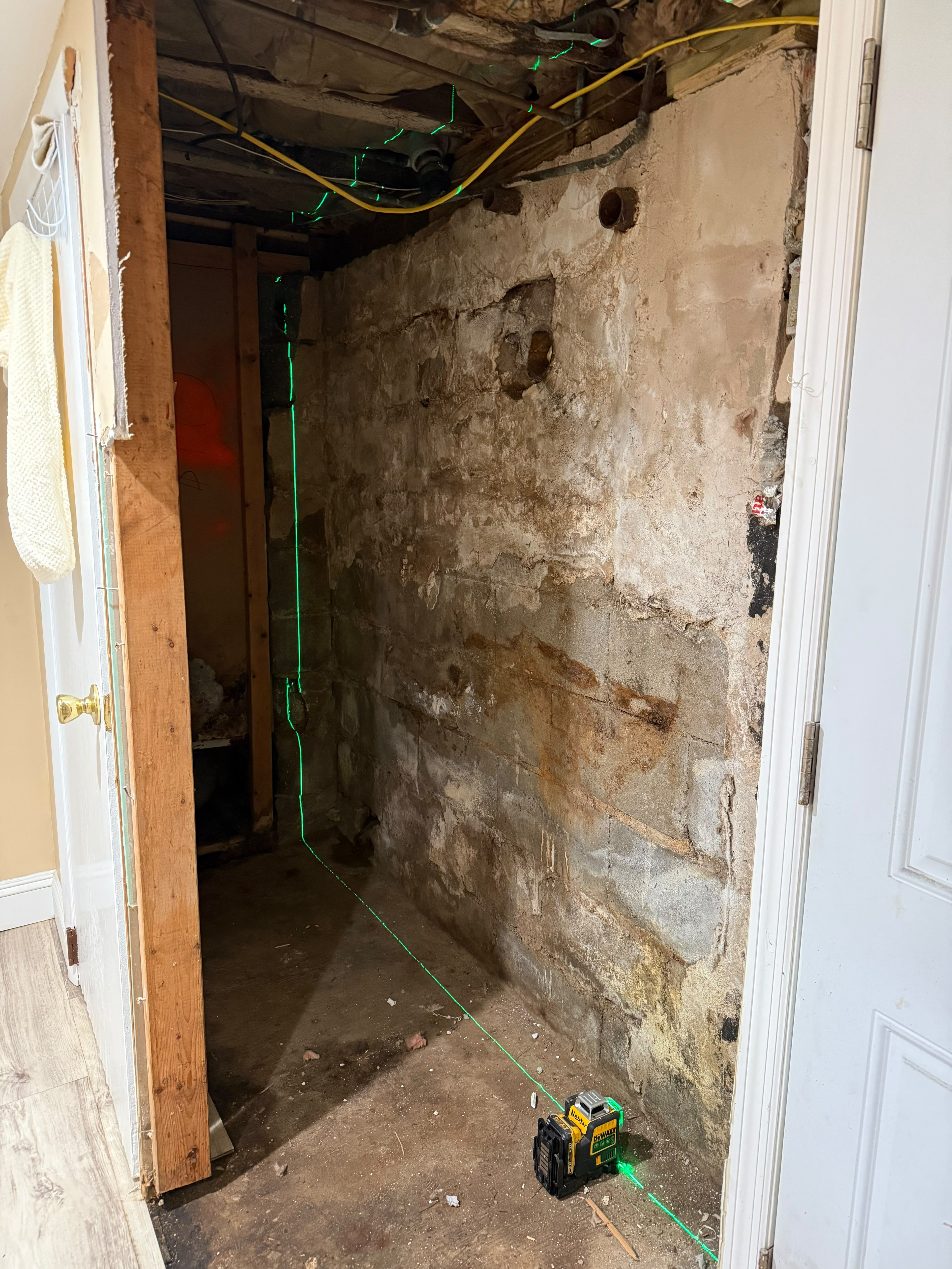 DeWalt 360 green cross-line laser level casting plumb and level guides on concrete block wall by LQJ General Construction