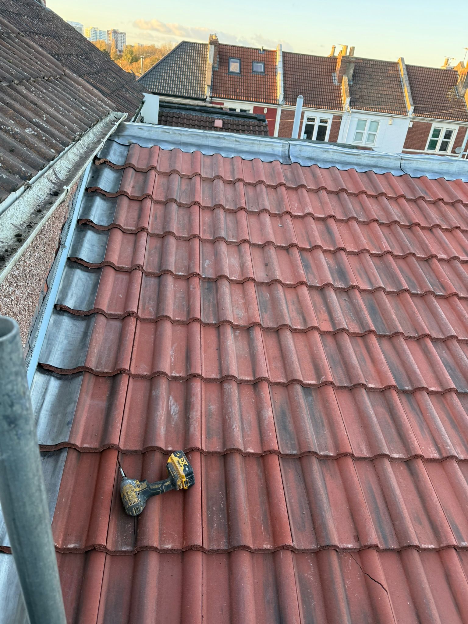 Red interlocking profile tiles with custom lead valley and abutment flashing